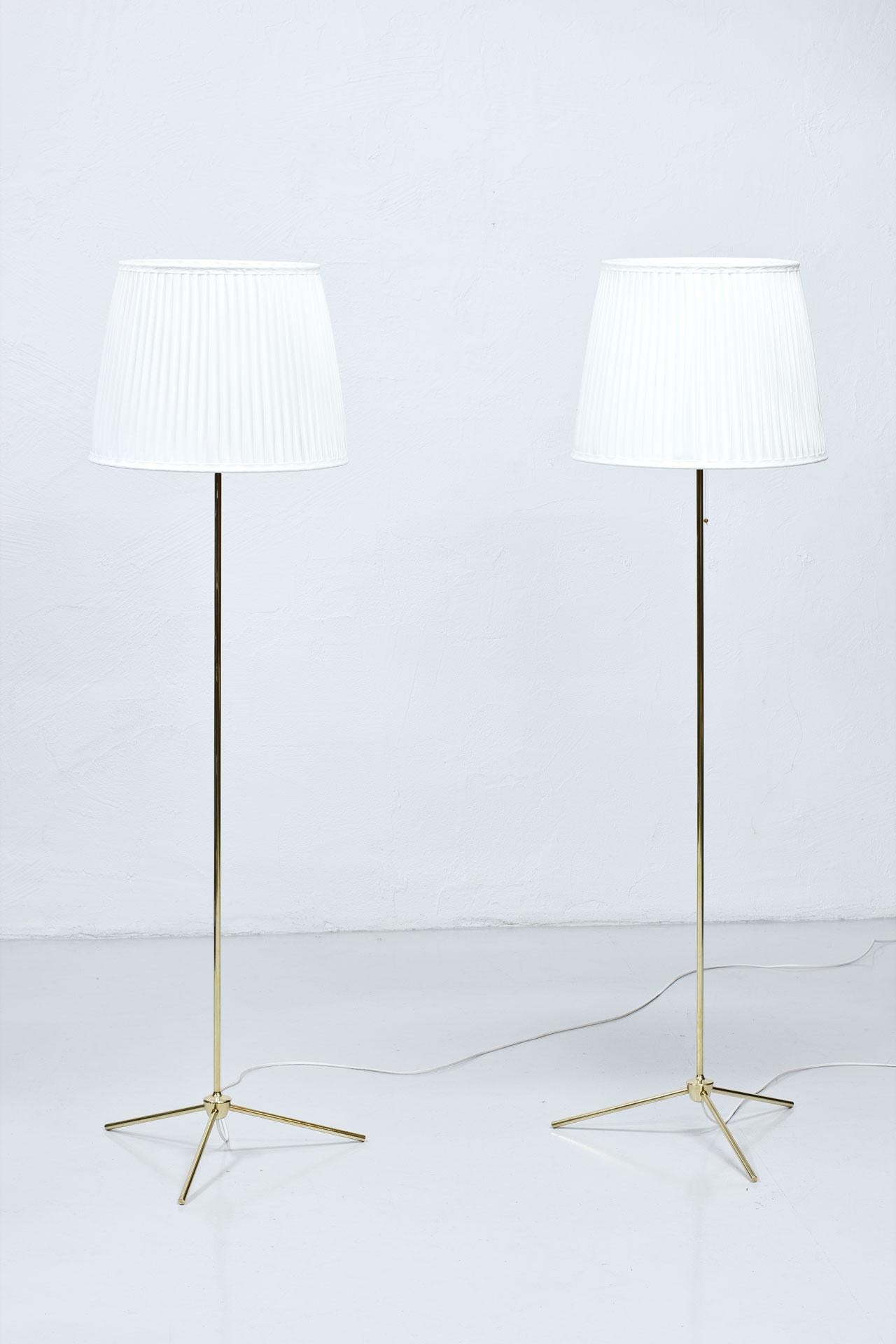 Rare pair of floor lamps model “G-302? manufactured by Bergboms in Sweden during the 1950s. Polished brass stem. New hand sewn, off–white pleated chintz fabric shades. Rewired.