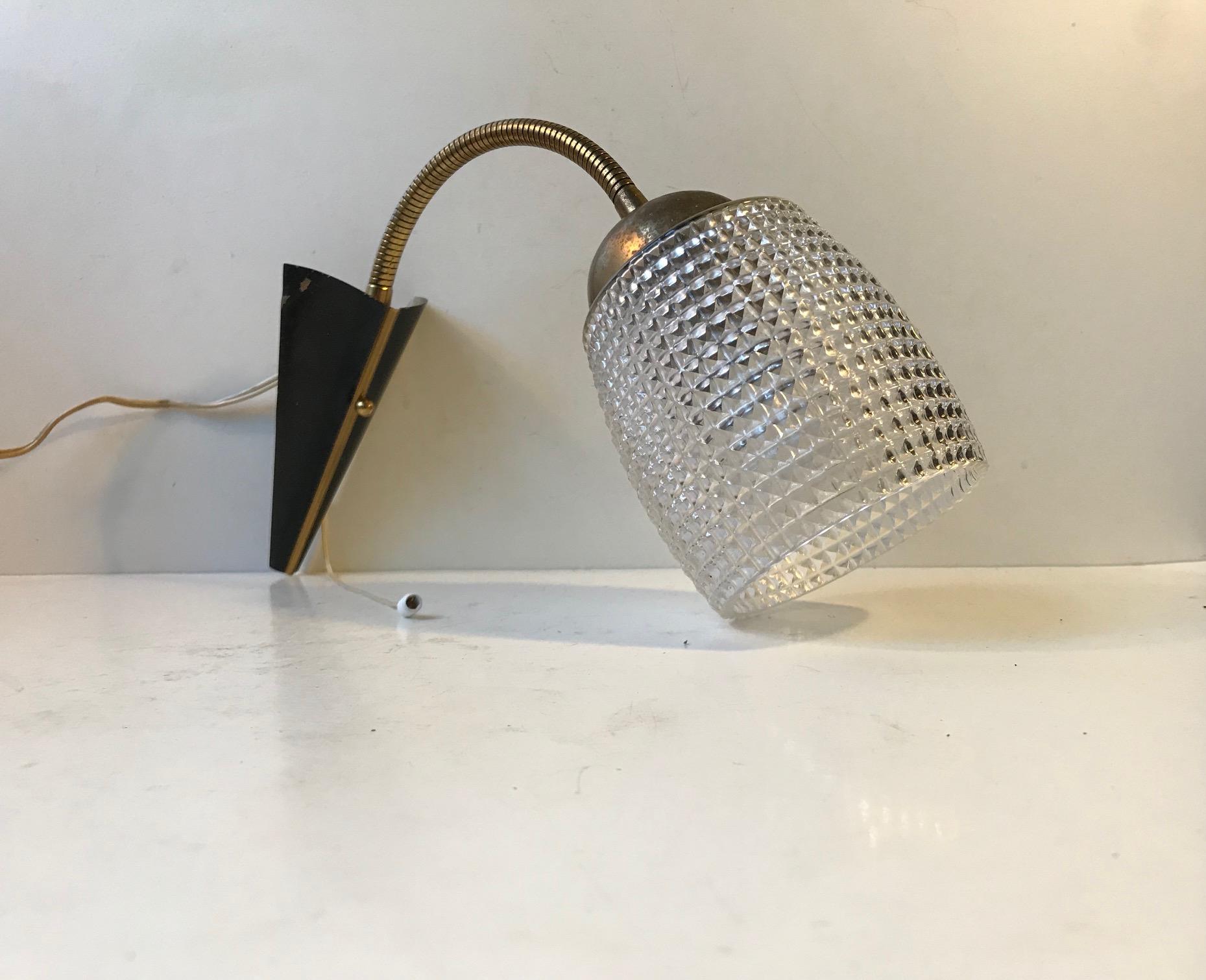 - Early 1950s wall light made in Scandinavia
- In a style reminiscent of Stilnovo
- Composed of partially black painted brass
- Mounted with a Waffle Pattern glass shade
- Adjustable in every direction due to the flexible brass swan neck.