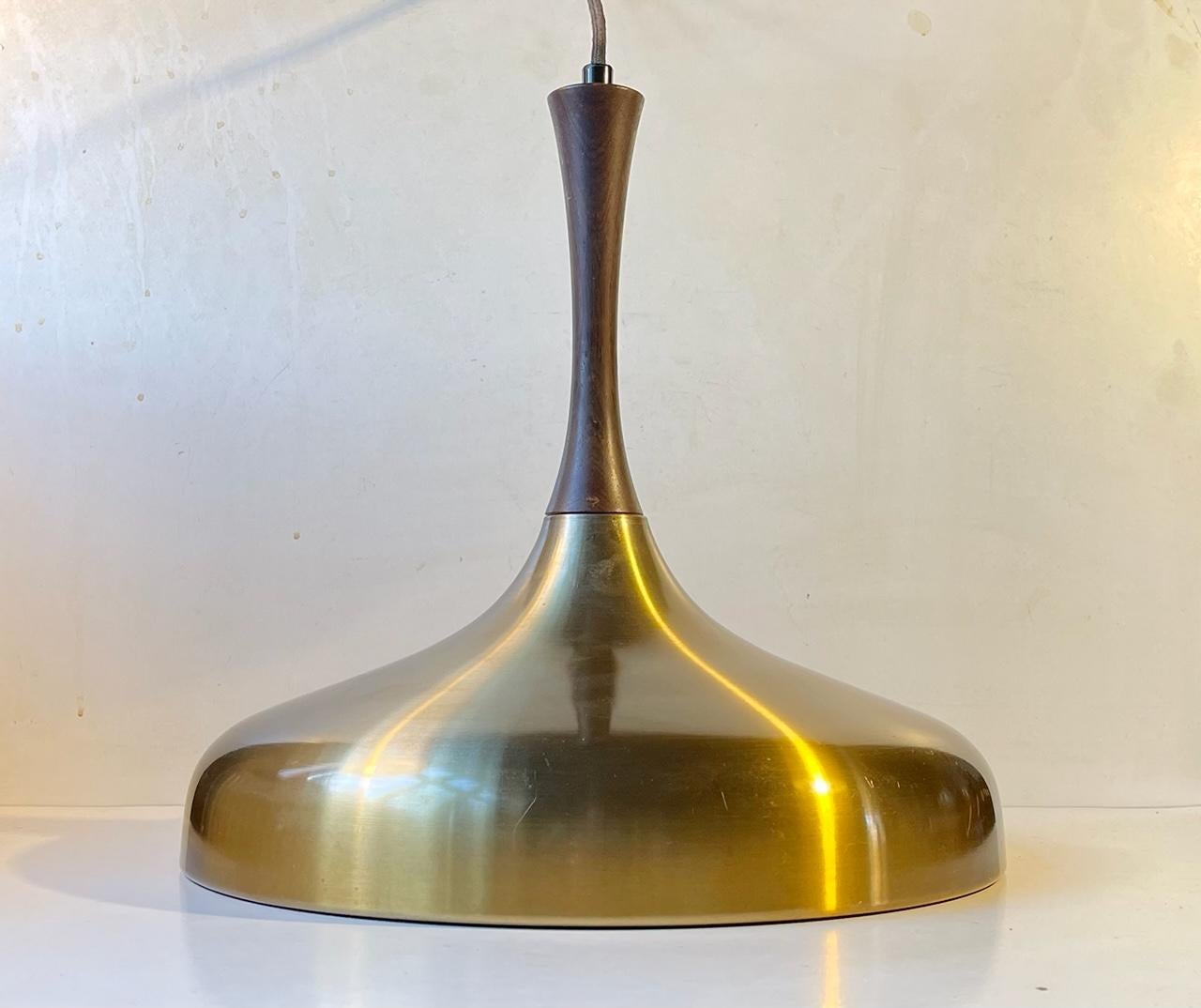 A rare ceiling pendant light composed of an organically shaped brass alloy aluminum shade set in a stylish elongated dark solid wooden top. Designed by Danish Ejnar B. Mielby during the late 1960s and manufactured by Lyfa in the early 1970s.