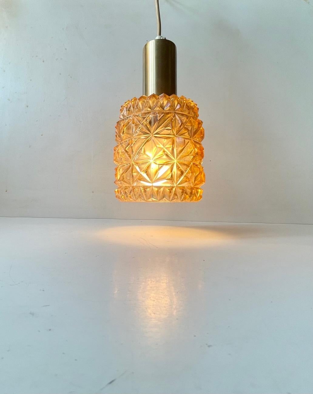 Piccola lampada a sospensione scandinava composta da vetro miele pressato a rombi e da un piano in alluminio legato all'ottone. Produttore/design scandinavo sconosciuto in uno stile che ricorda Orrefors e Carl Fagerlund. È dotato di una lampadina