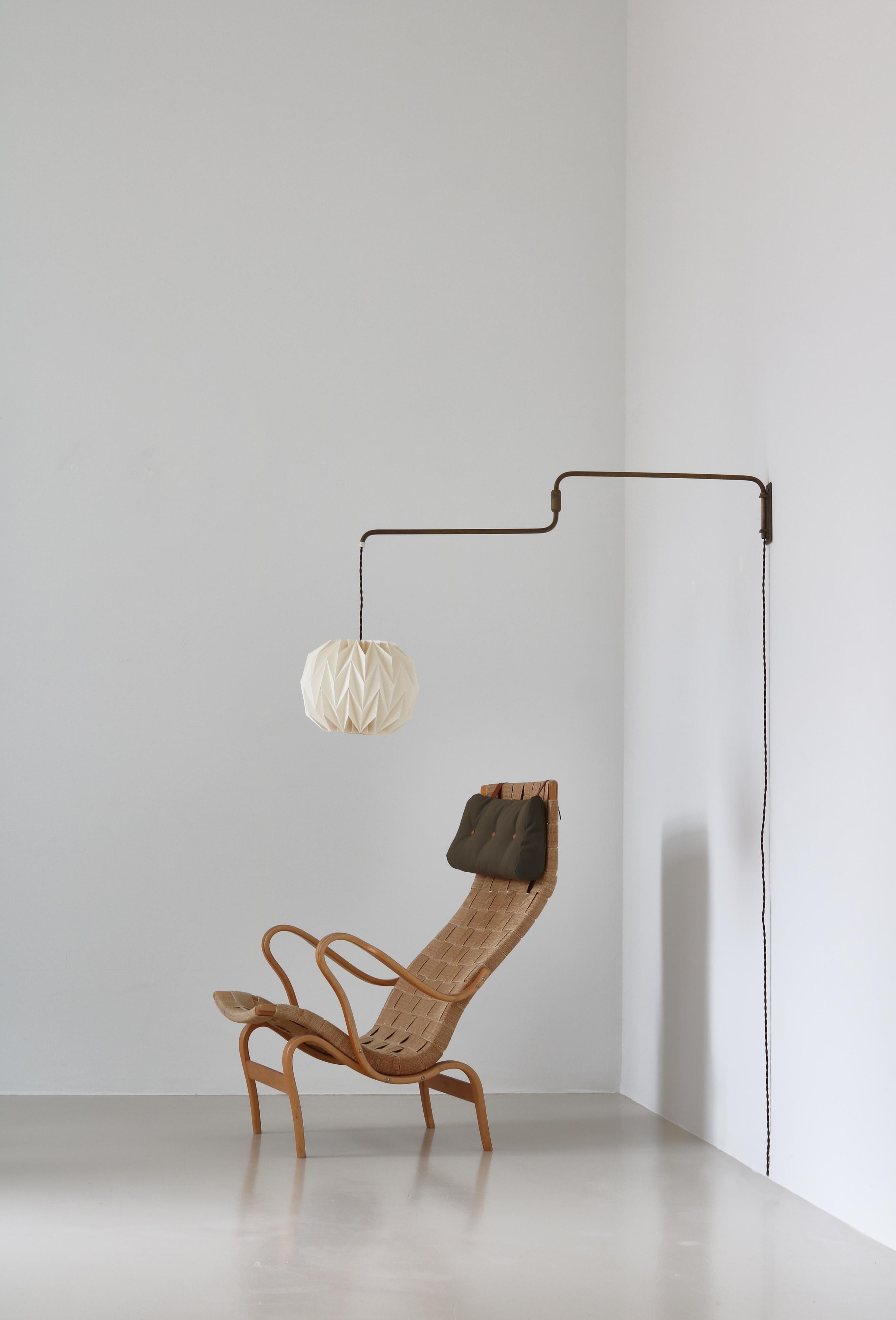 Scandinavian Modern swing arm brass lamp from the 1950s with a hand folded Le Klint shade. The lamp can be adjusted in different directions and the cord can be height adjusted simply by pulling. Beautiful patina to the solid brass. In the style of