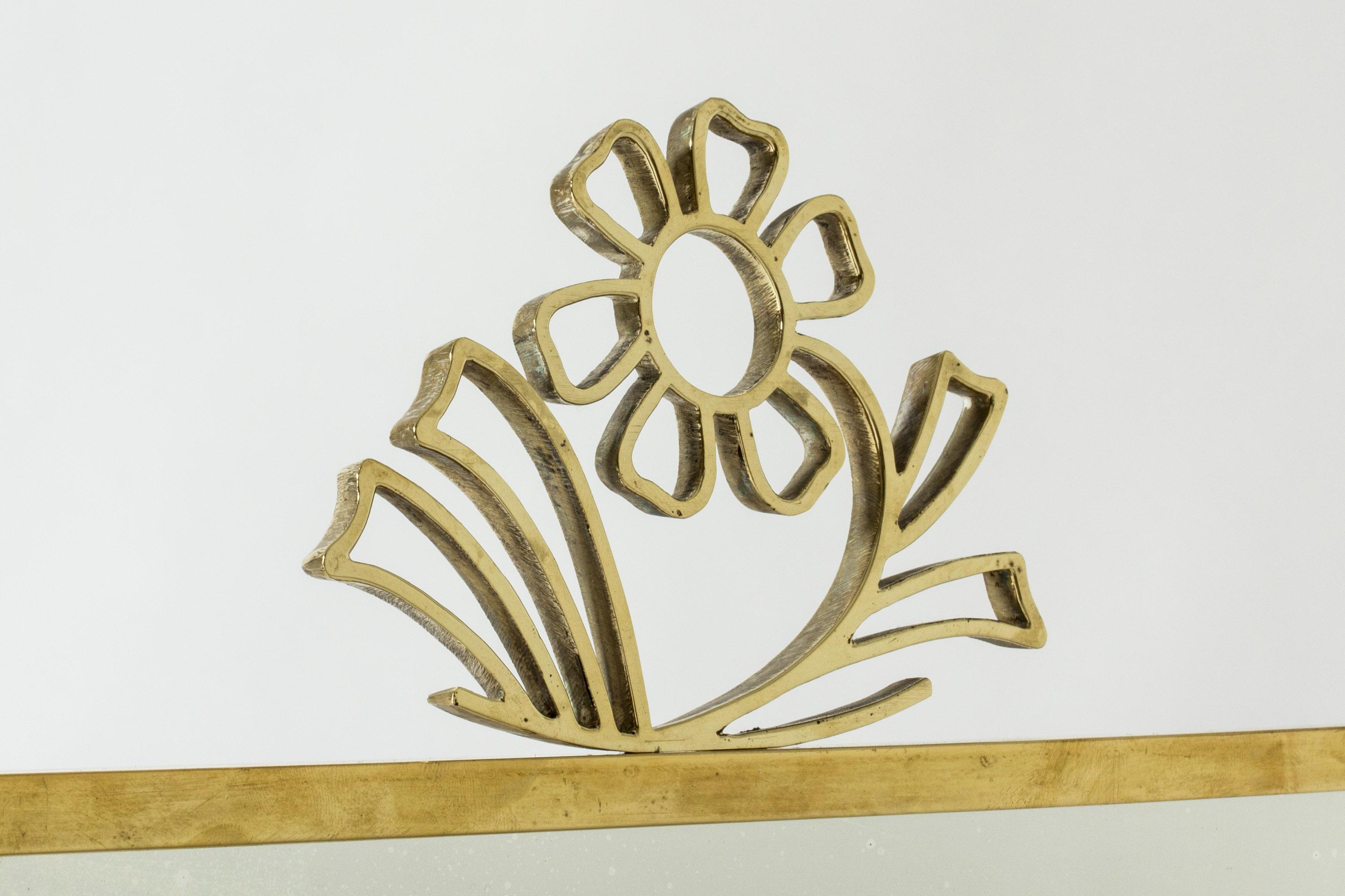 Brass wall mirror by Lars Holmström, in a clean form. Adorned with a lovely stylized flower at the top.