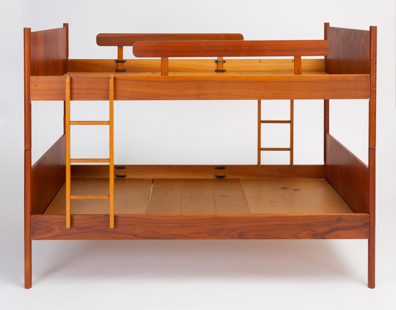 This set of Norwegian twin-size bunk beds has teak head- and foot-boards, dowel legs, side rails, and attached nightstands with a shelf and rounded corners. A small ladder fits to the rails of each side of the stacked beds for access to the top