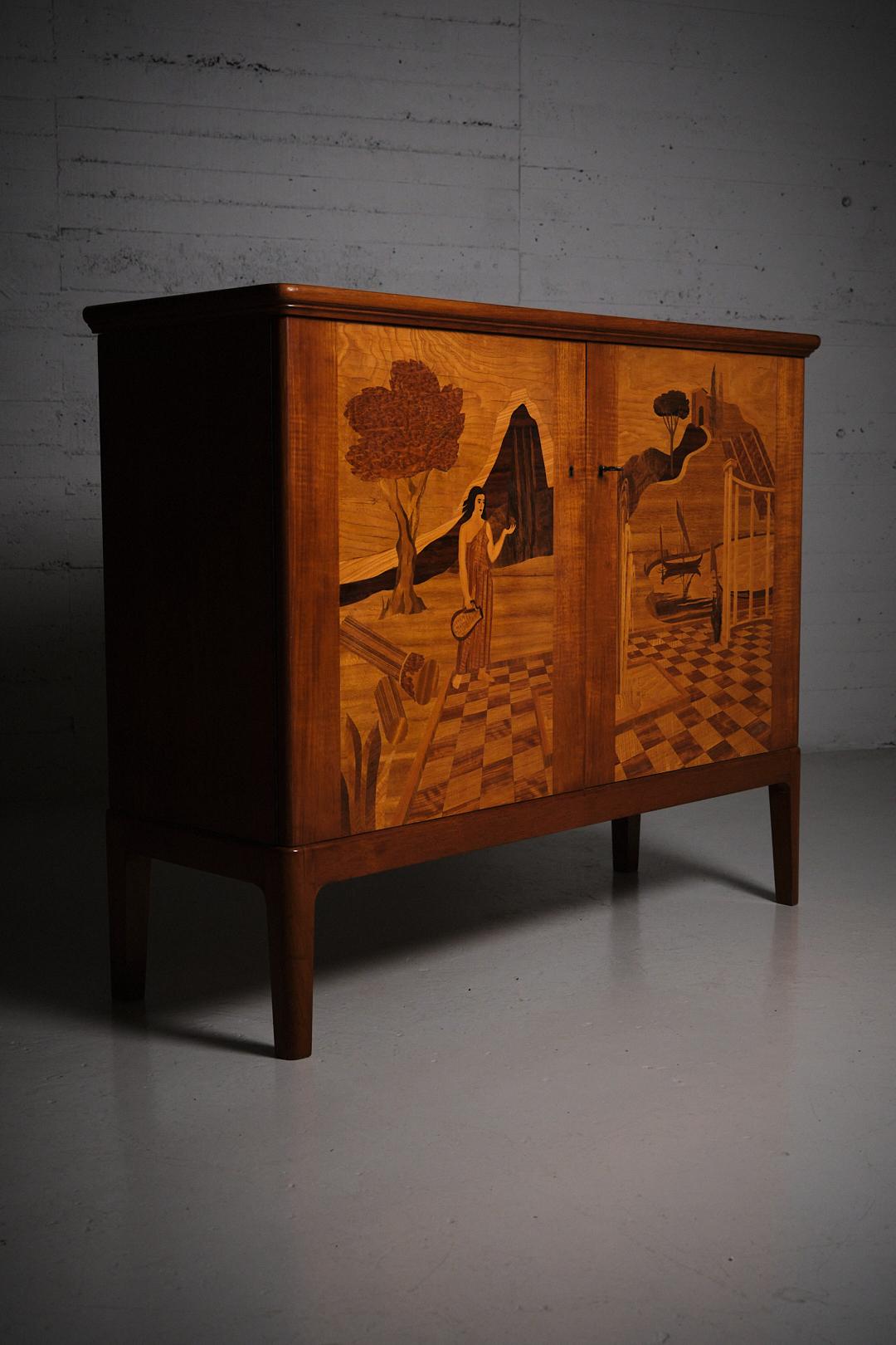 Eccezionale mobile o credenza disegnato da Erik Mattsson e realizzato da Mjölby Intarsia in Svezia negli anni '40. 

Bellissimi intarsi in legno sulle porte. Chiave inclusa.

Una delle due chiusure della porta è rotta sulla porta sinistra. Si apre e