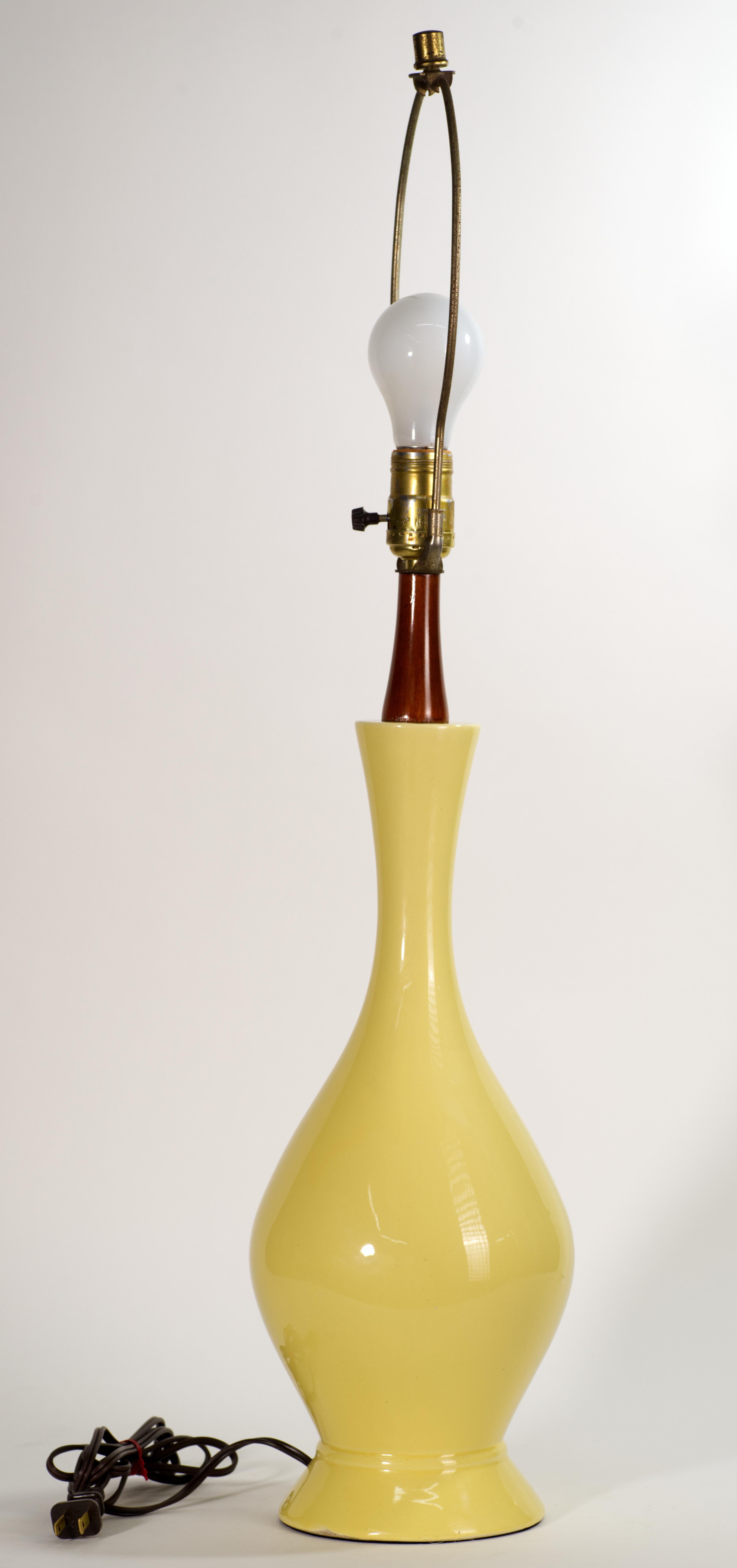 The Vintage Scandinavian Modern, Danish style ceramic lamp features elongated ceramic body with build-un ceramic round base and wood top element. Le corps sculptural en céramique est décoré d'une glaçure monochrome jaune beurre moyennement