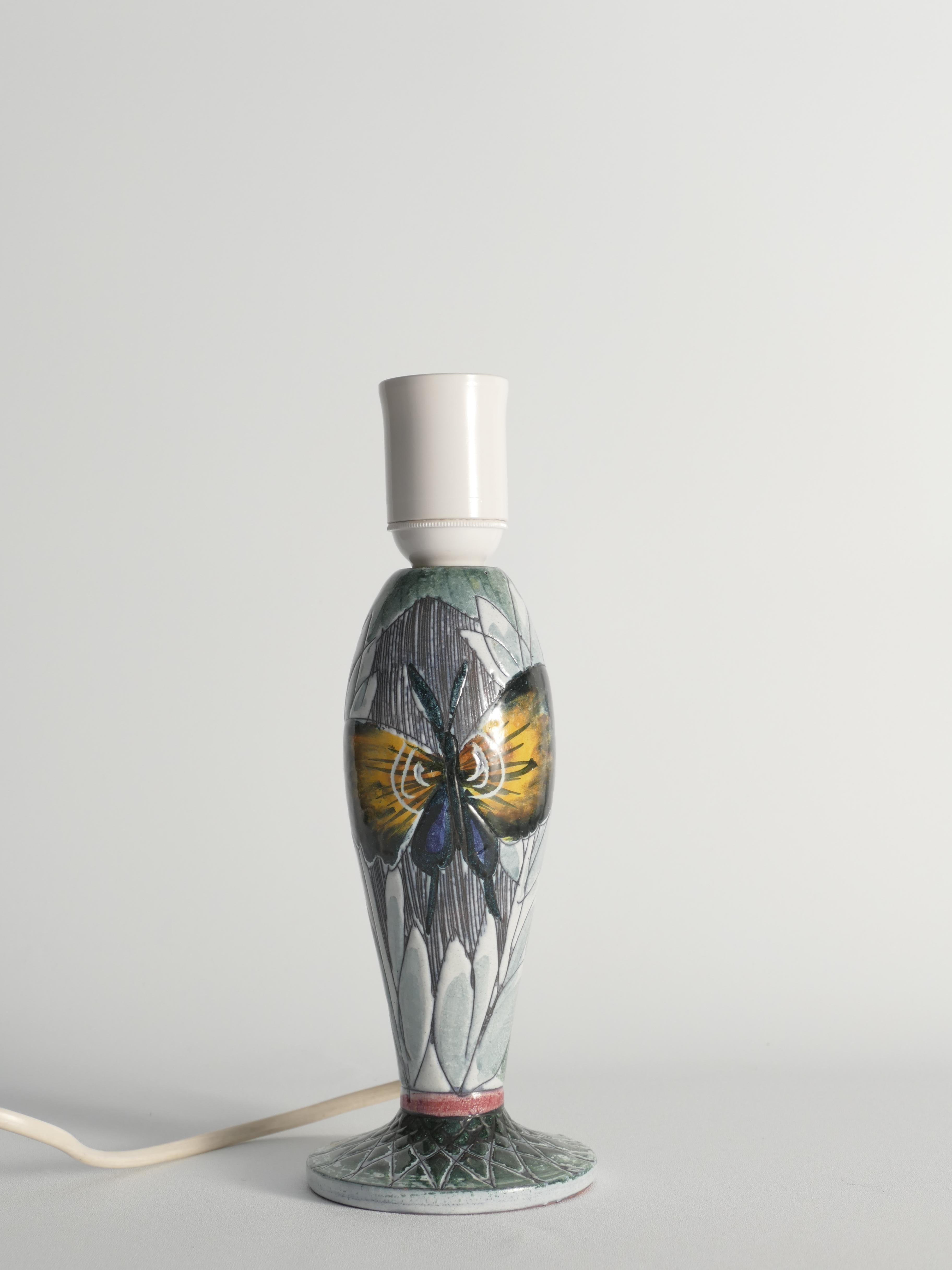This unique Scandinavian Modern table lamp was crafted by Tilgmans Keramik in Sweden during the 1950s. The curvaceous earthenware base is hand-decorated in a sgraffito technique, showcasing a vivid yellow and blue butterfly against a backdrop of
