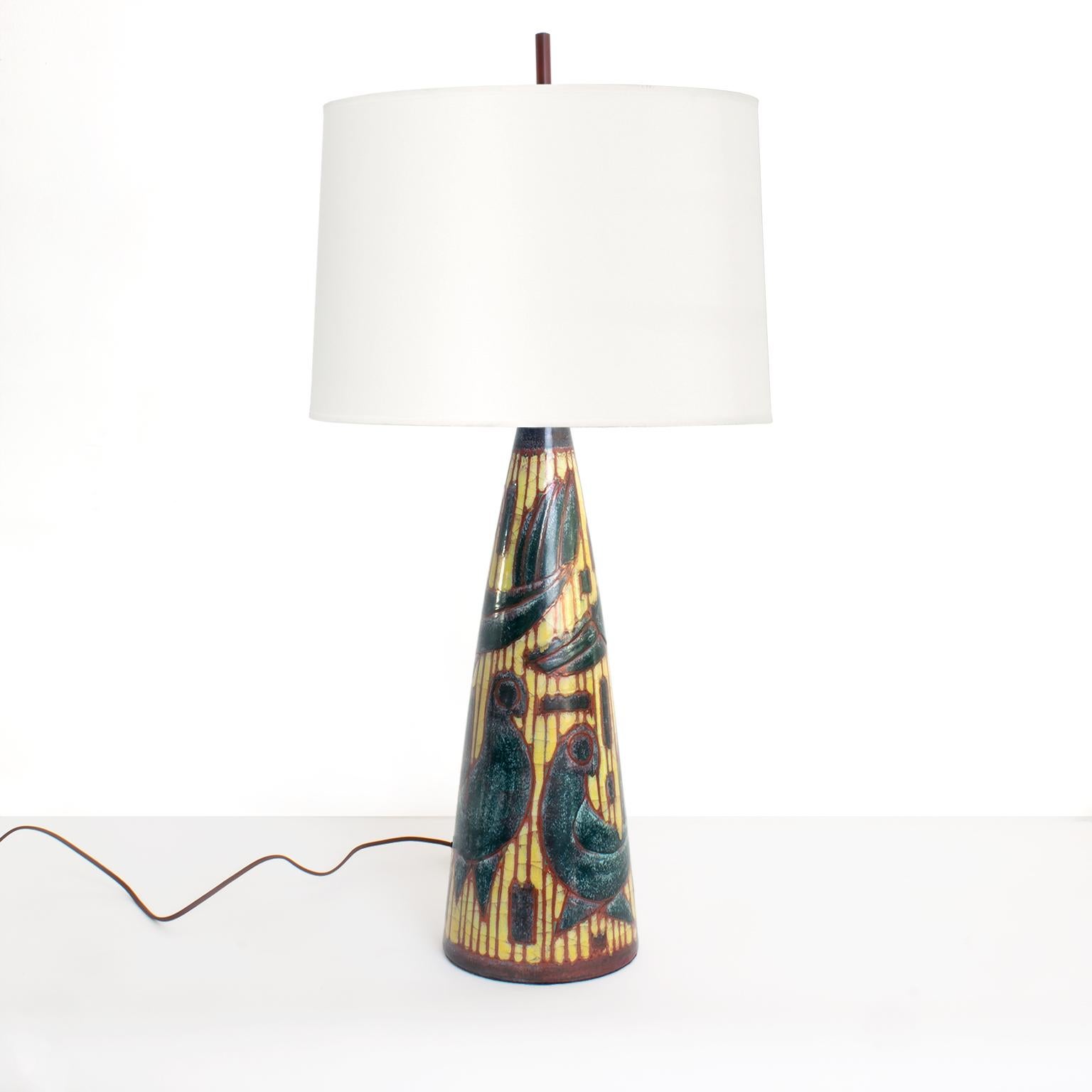 Beautifully hand decorated Scandinavian Modern ceramic lamp designed by Marianne Starck for Michael Andersen, Bornholm, Denmark. The lamp depicts several birds against a golden background perched inside a red cage. The lamp has custom hand patinated