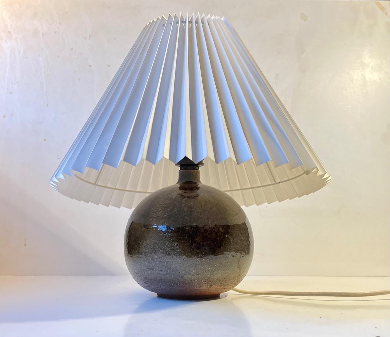 Spherical ceramic table light decorated with earthy polychrome glazes. It was designed by Jette Hellerøe and manufactured by Axella in Denmark during the 1970s. The base is signed by the maker. The height of 30 cm is without shade. The base diameter