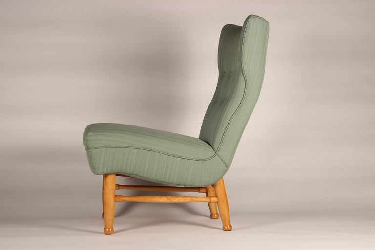 A comfortable and low level lounge chair by Elias Svedberg in the Scandinavian Modern Design Style. The design was produced by Stockholm’s high end department store Nordiska Kompaniet (NK), who manufactured and retailed furniture designs by a number