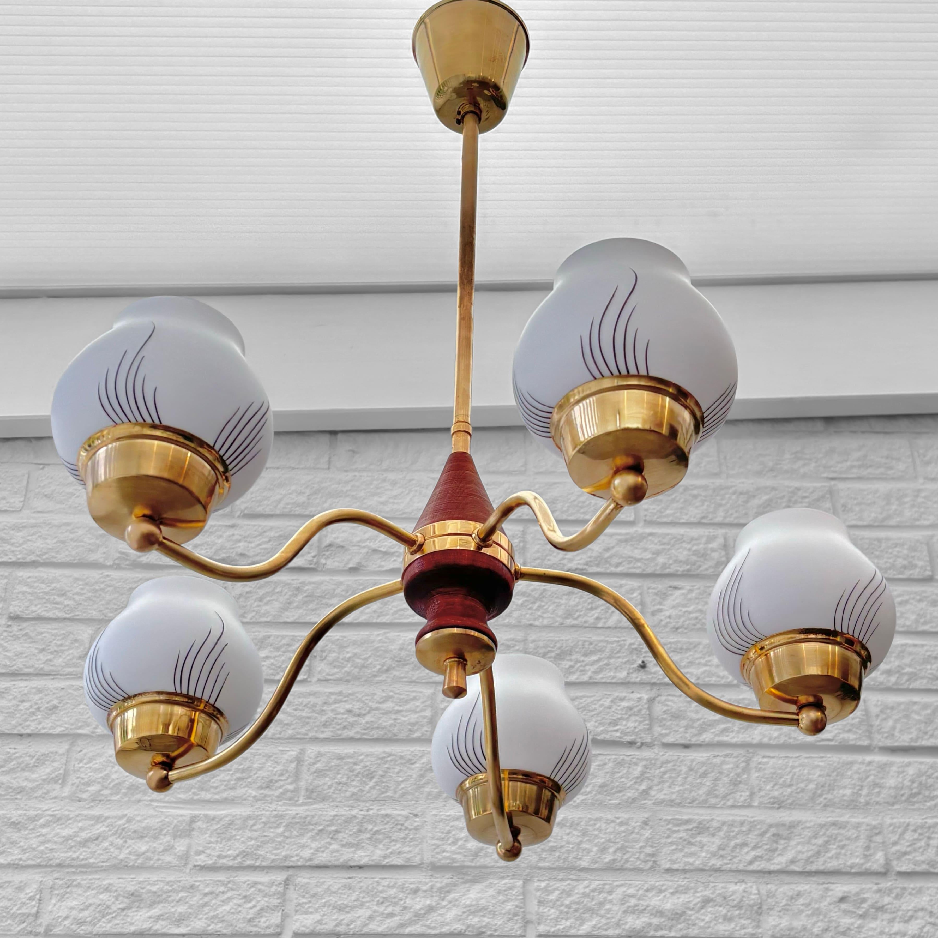 Un bellissimo lampadario scandinavo di metà secolo, prodotto da un fabbricante svedese non identificato negli anni '40. Realizzato in ottone, presenta cinque bracci graziosamente curvi che si estendono da un obelisco centrale in legno tinto.