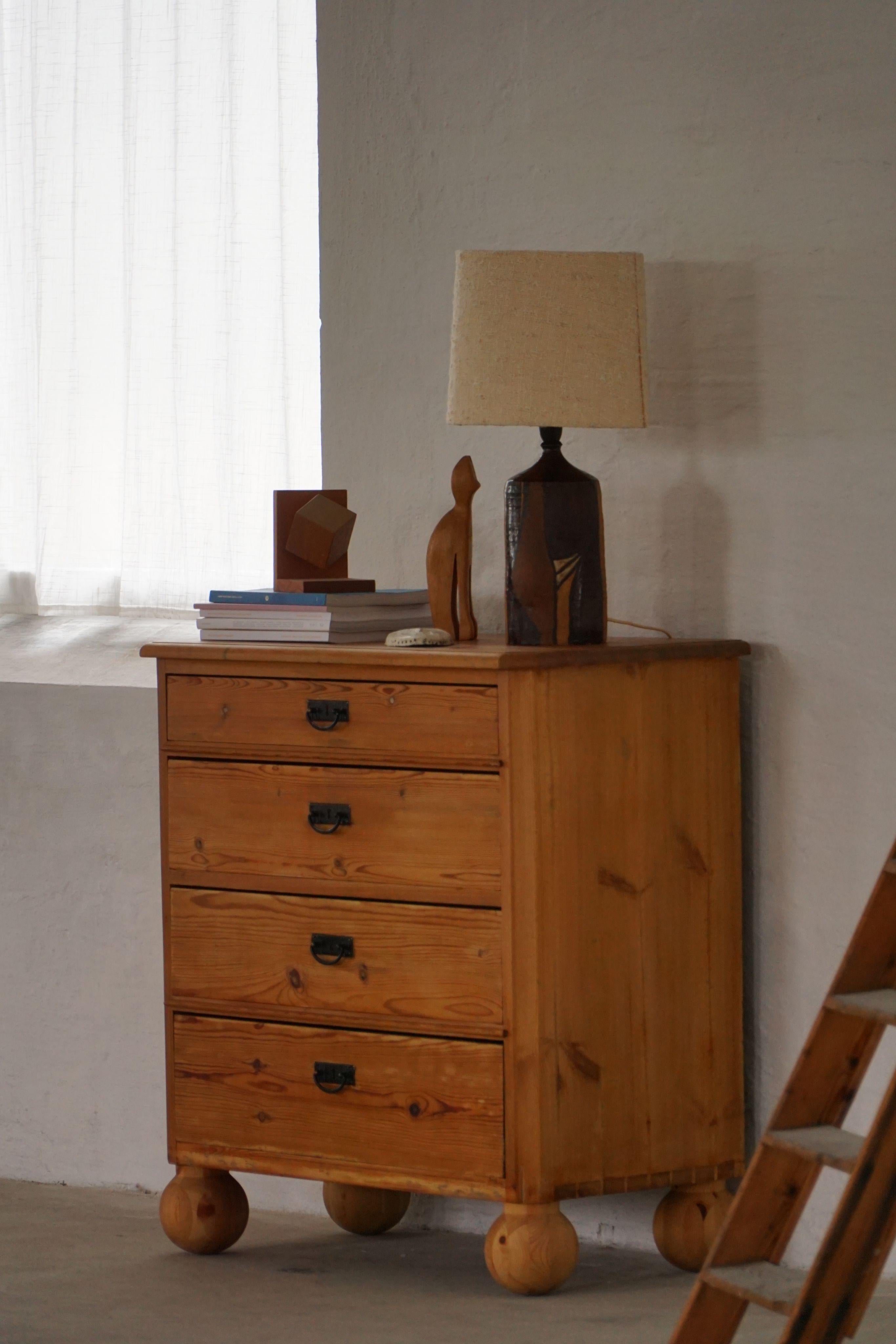A charming Danish pine chest of drawers dating from the early 20th century, thoughtfully updated with a creative twist. While the body retains its original character and rich grain, the base now rests on four oversized wooden ball feet—an