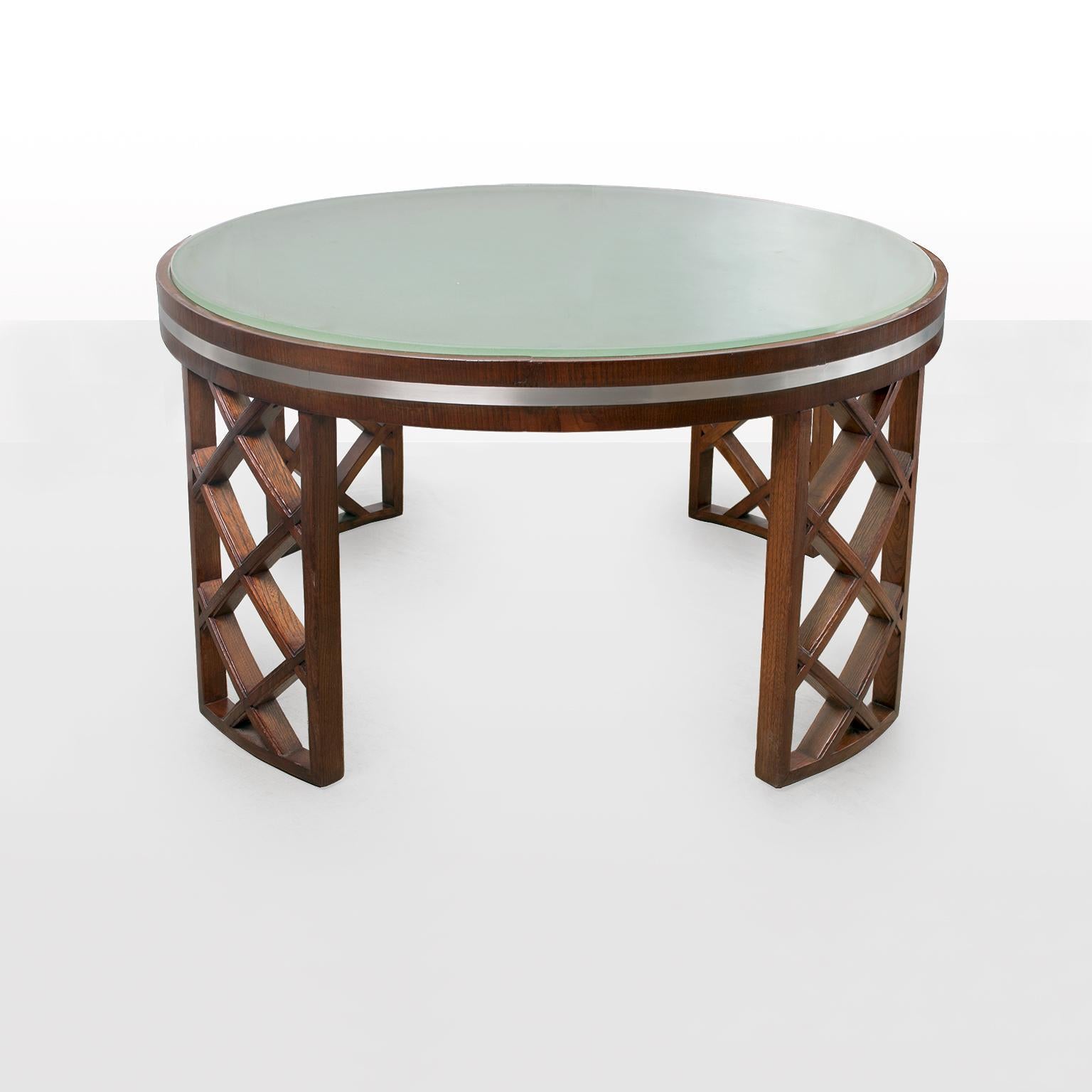 Swedish Art Deco coffee table in stained elmwood. Legs are constructed with a lattice framework. A band of metal accents the top which has a heavy acid etched glass top inserted. Measure: Diameter 37.5
