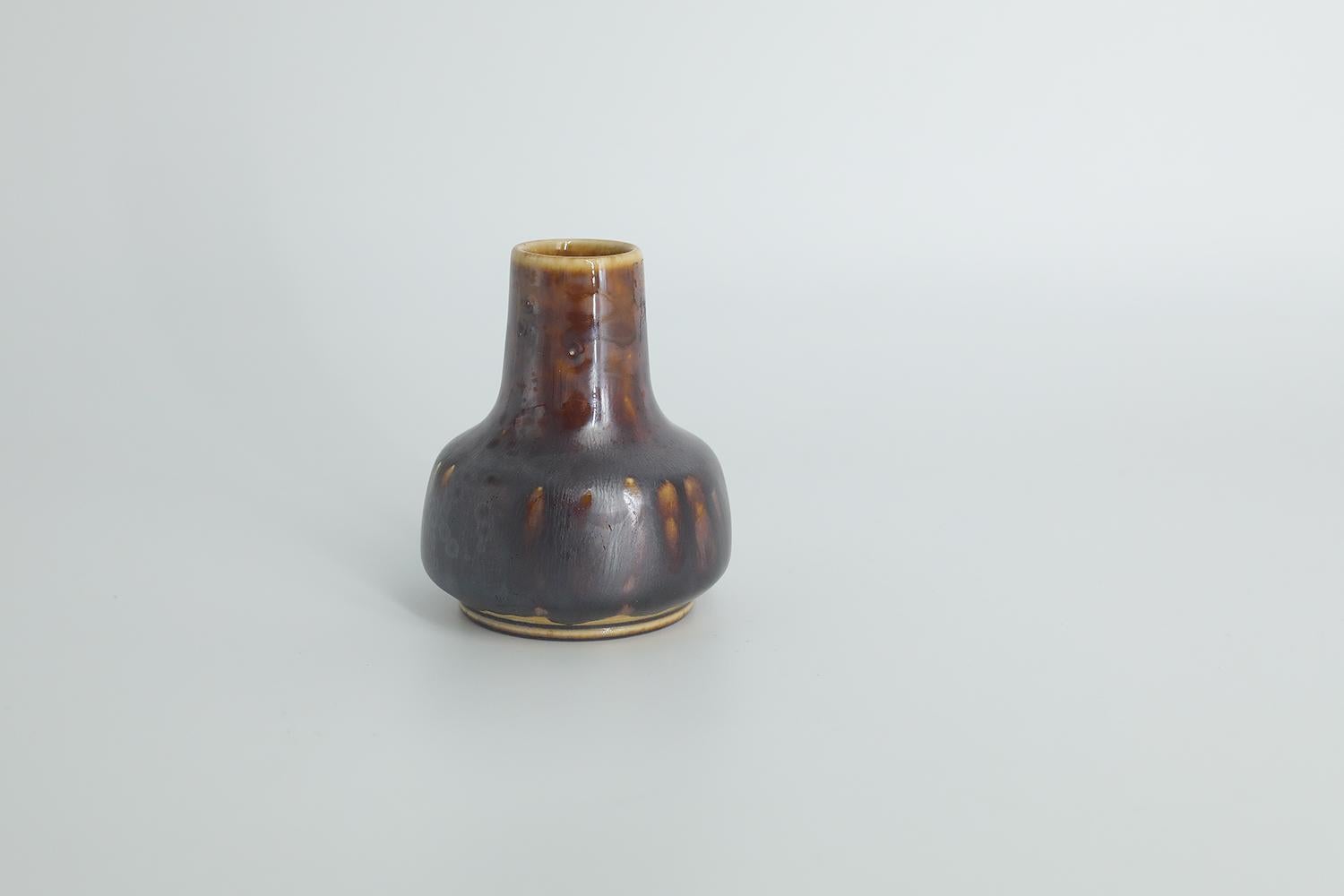 This miniature, collectible stoneware vase was designed by Gunnar Borg for the Swedish manufacture Höganäs Keramik during the 1960s. Handmade by a Master, with the utmost care and attention to details. This vase dyed brown in an irregular shade.