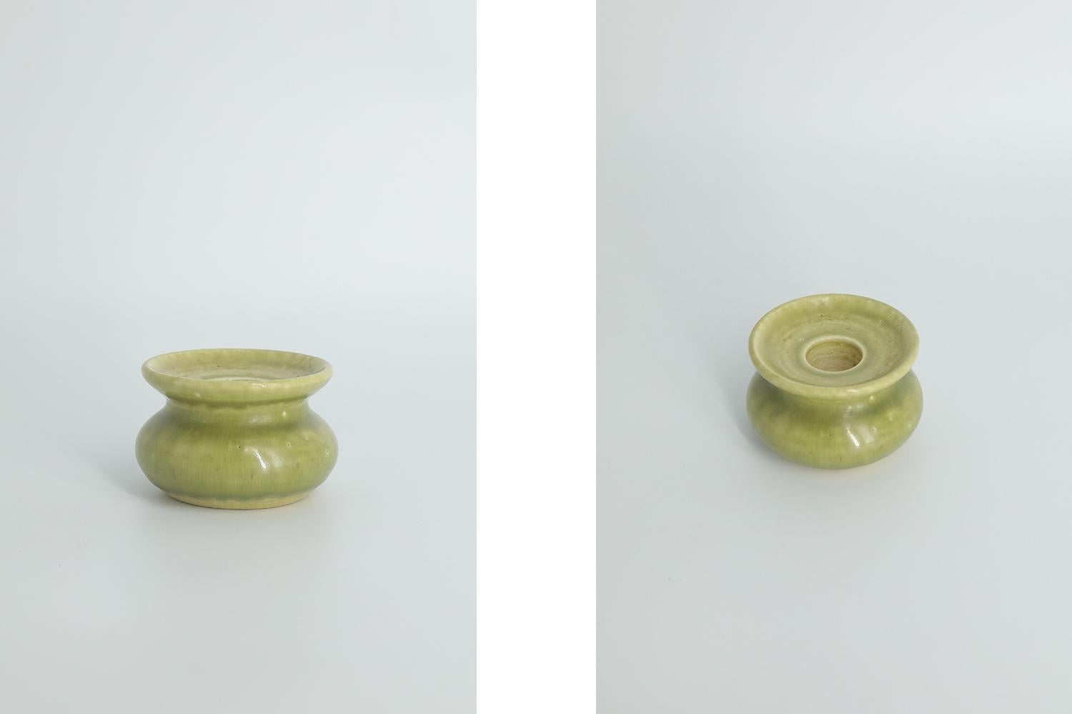 This miniature, collectible stoneware candleholder was made by the Swedish manufacture Gunnars Keramik Höganäs during the 1960s. Handmade with the utmost care and attention to detail. A bulging candlestick colored light green in an irregular shade.