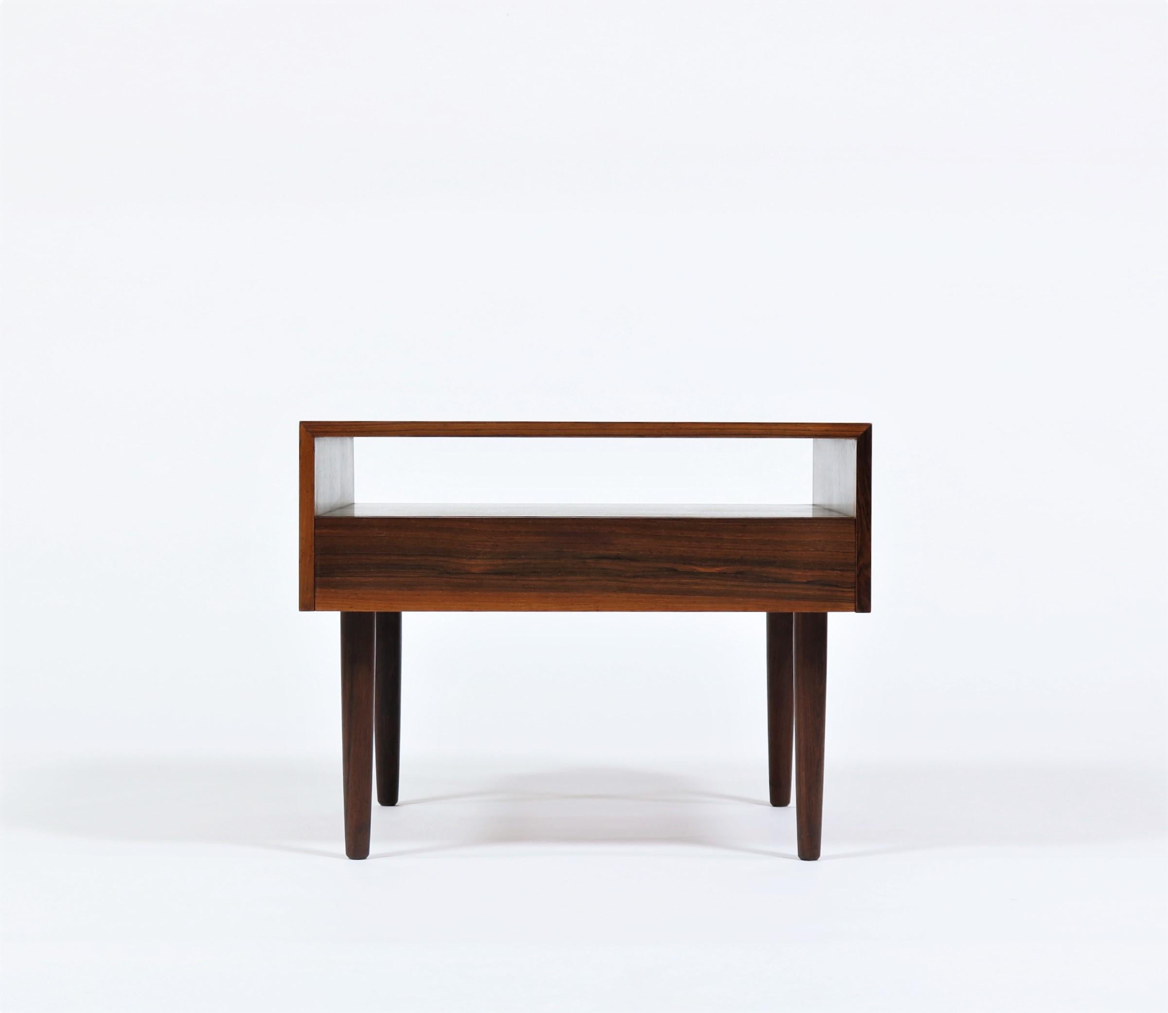 Cool and elegant side/end table made in Denmark in the 1960s in beautifully grained Rosewood. The style is typical for Danish Modern furniture of the era and designers such as Kai Kristiansen, Arne Vodder or Aksel Kjersgaard.