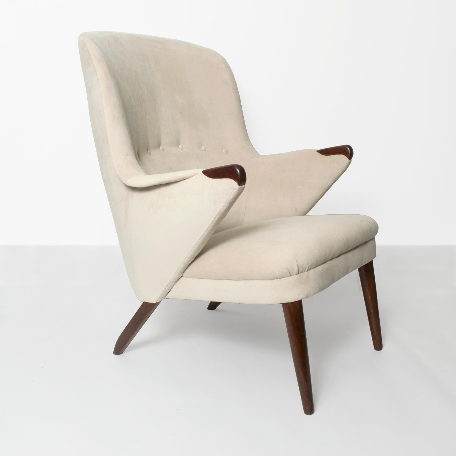 An elegant Scandinavian Modern lounge chair with curved backrest detailed with covered buttons. Legs and hand rest are carved stained solid teak. Newly restored and re-upholstered in cream colored velvet fabric. 
Measures: Height: 37