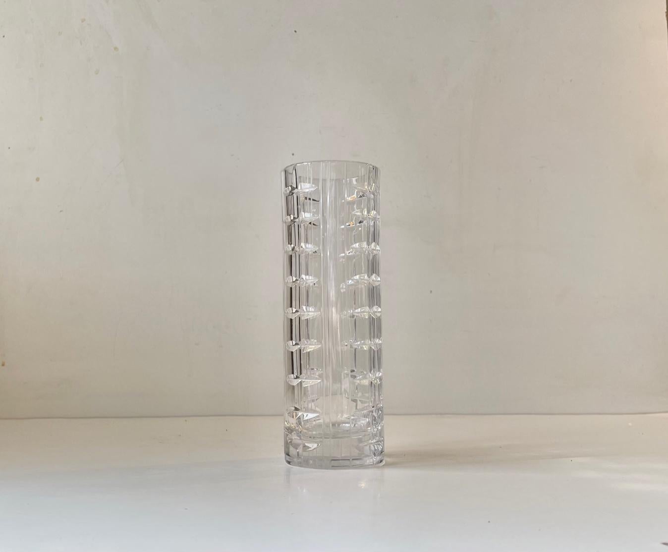 A cut crystal torpedo shaped vase presumably from either Kosta Boda or Orrefors. It features diffrent techniques most prominent the mix of vertical ribbings and geometric patterns. It measures 17.5 cm in height and has a diameter of 6 cm.
