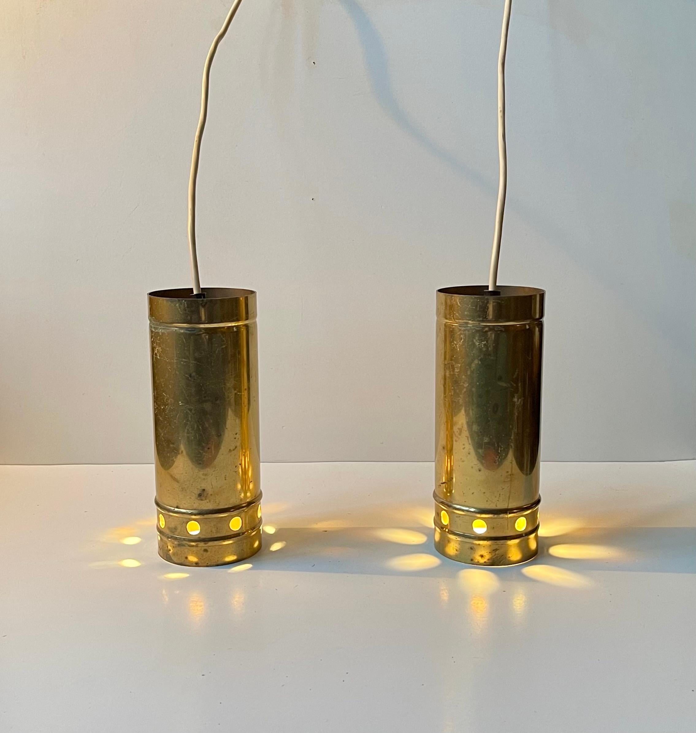 Insolite lampade a sospensione cilindriche in ottone. Eleganti perforazioni circolari che creano un'esperienza di luce accogliente. Lo stile ricorda Hans-Agne Jakobsson, Paavo Tynell e Svend Aage Holm Sørensen.   

Misure: H. 20 cm, Diametro 8 cm. 