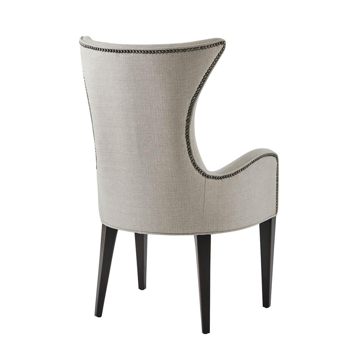 An ebonized and upholstered dining chair, the waisted curved back, above a tight seat and padded arms, on square tapering legs. With a performance fabric and antiqued steel nailheads.

Dimensions: 24.5
