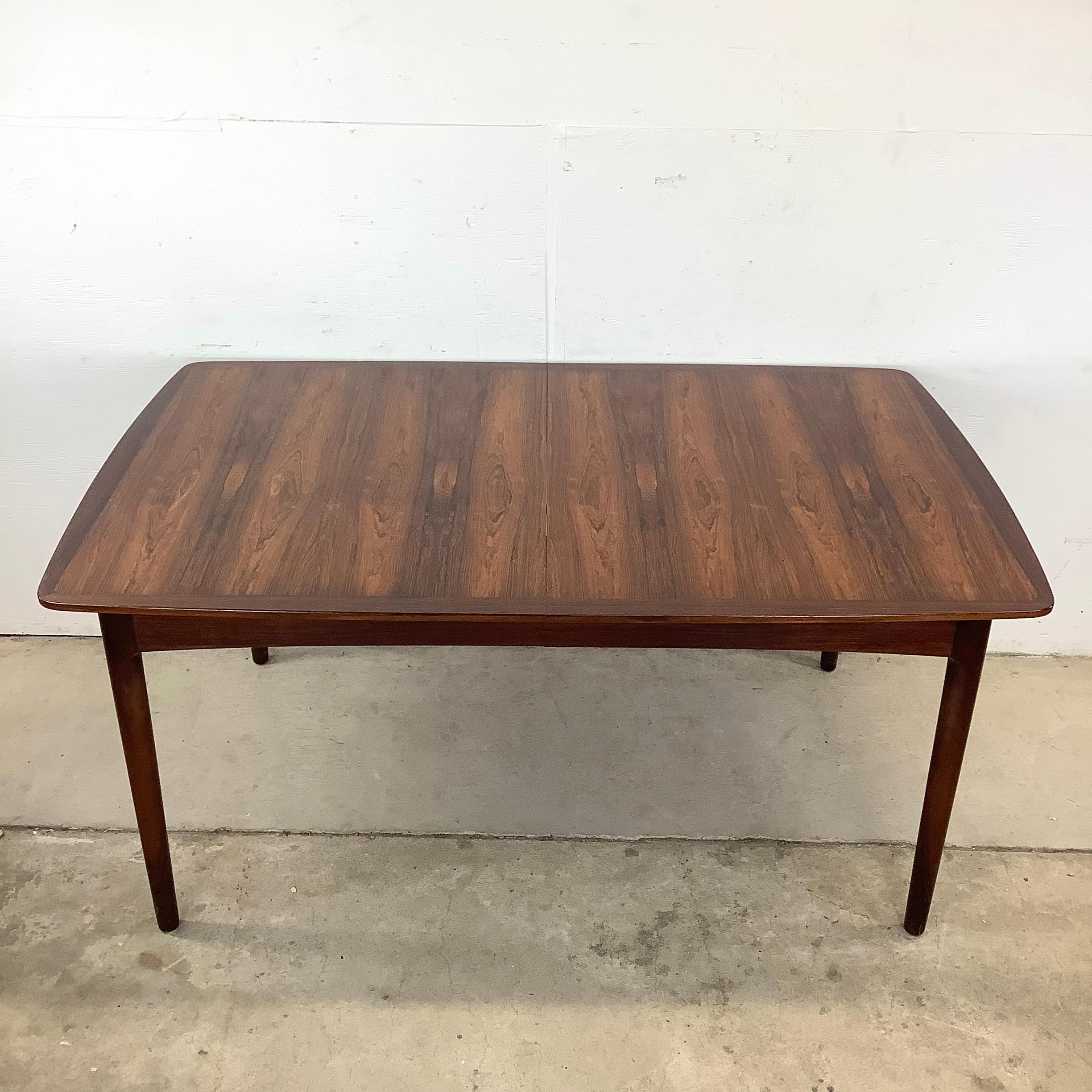 Striking in both form and function, this Scandinavian Modern rosewood dining table is a mid-century masterpiece. The rich, natural wood grain brings warmth and character to the piece, creating a timeless centerpiece for any dining space. Designed