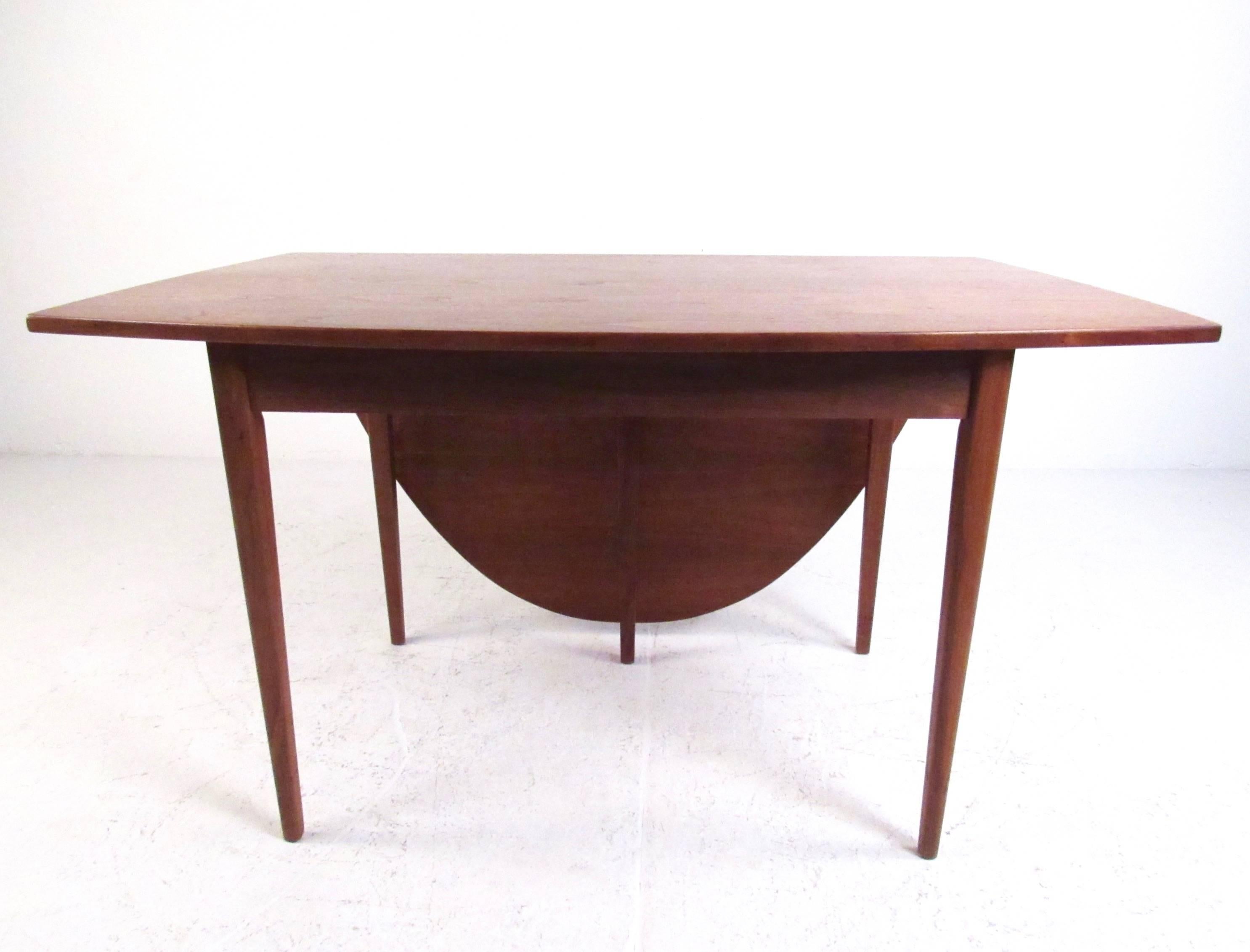 This midcentury drop-leaf table features Scandinavian teak construction and stylish Danish design. The free edge triangular shape of this vintage modern table creates a demilune effect and makes a striking addition to any room. Please confirm item