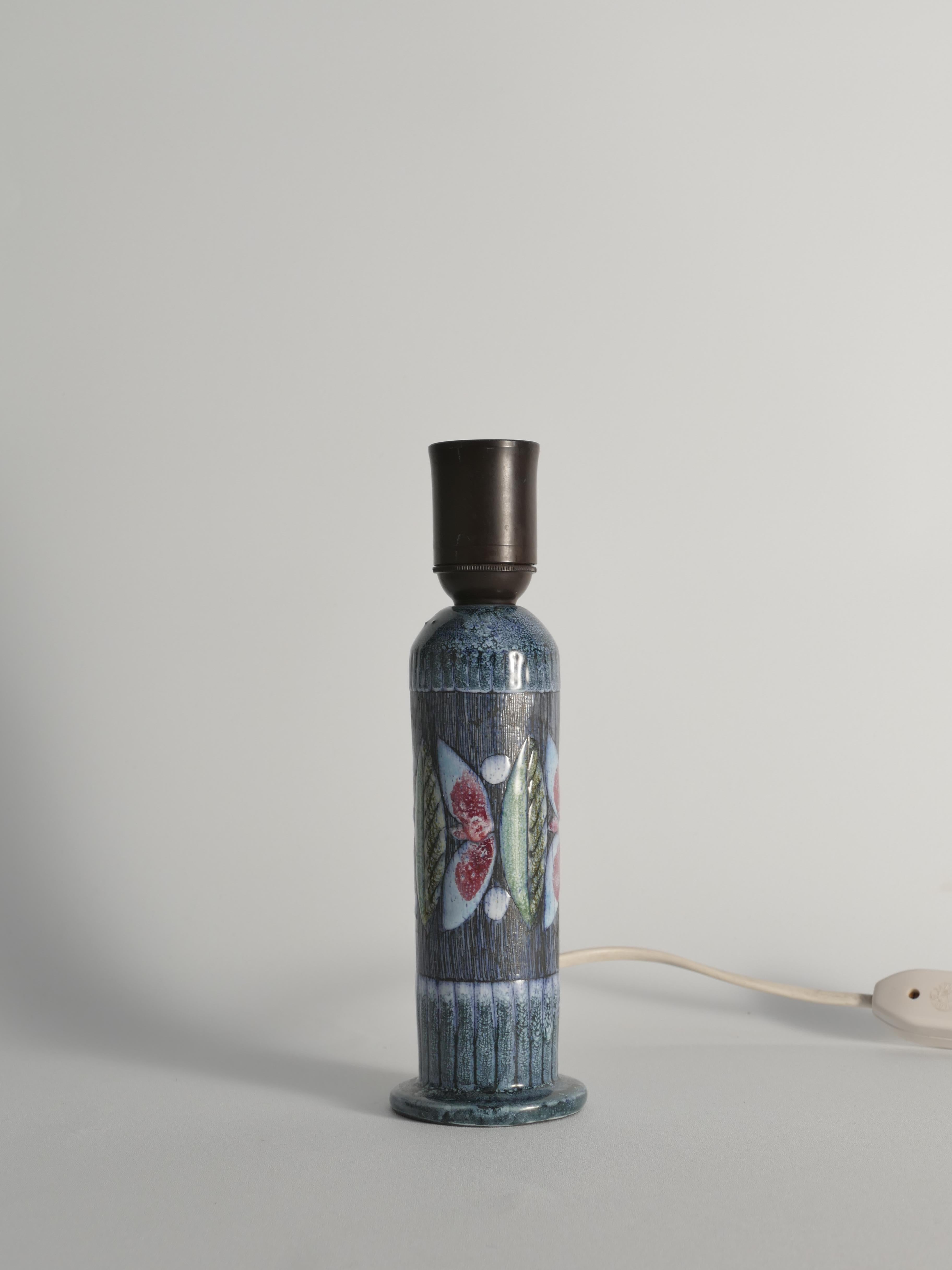 This handmade Scandinavian Modern earthenware table lamp was produced by Tilgmans Keramik in Sweden during the 1950s. Cylindrical in form, the lamp is decorated with a hand-sgraffito pattern featuring stylized butterflies and leaves in soft red,