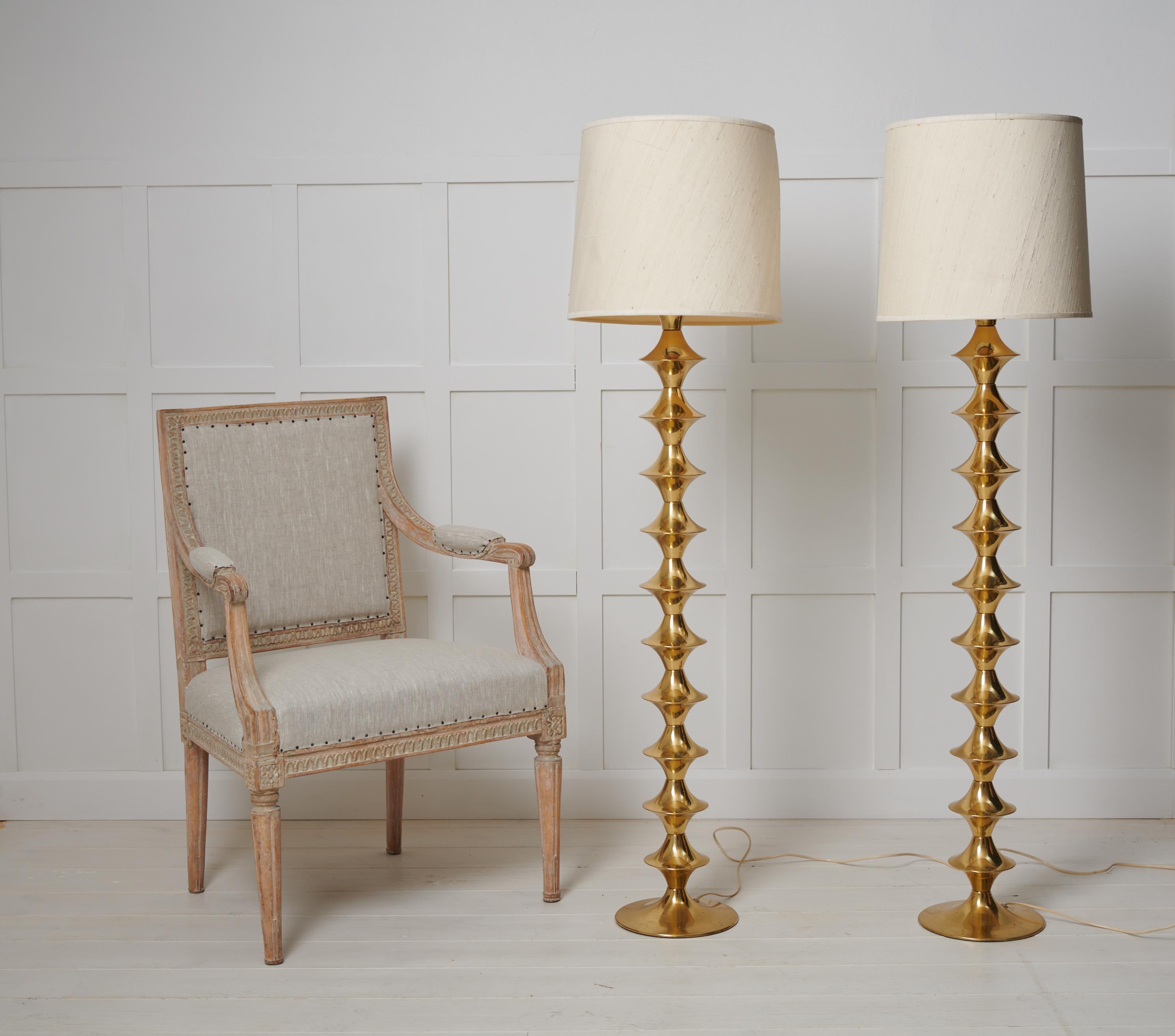 Scandinavian modern pair of brass floor lamps from Elit AB, made in Sweden around 1960s. The lamps are a classic midcentury design and can be used both side by and side and framing other interior objects. The base is a solid brass pole with a wavy