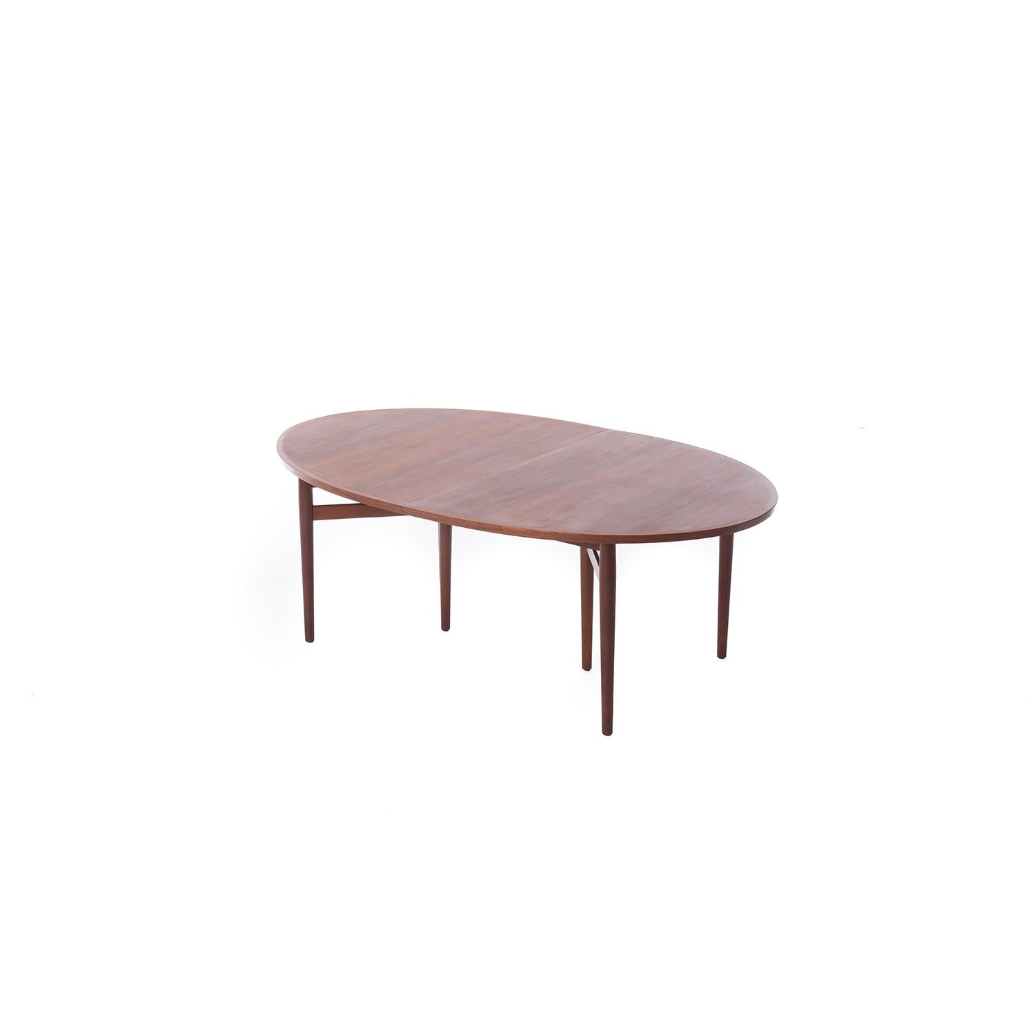 This Classic Scandinavian Modern ellipse shaped dining table designed by Arne Vodder (model 2121) has an inset double triangle shaped base and two insertable leaves. At full size this table reaches 117