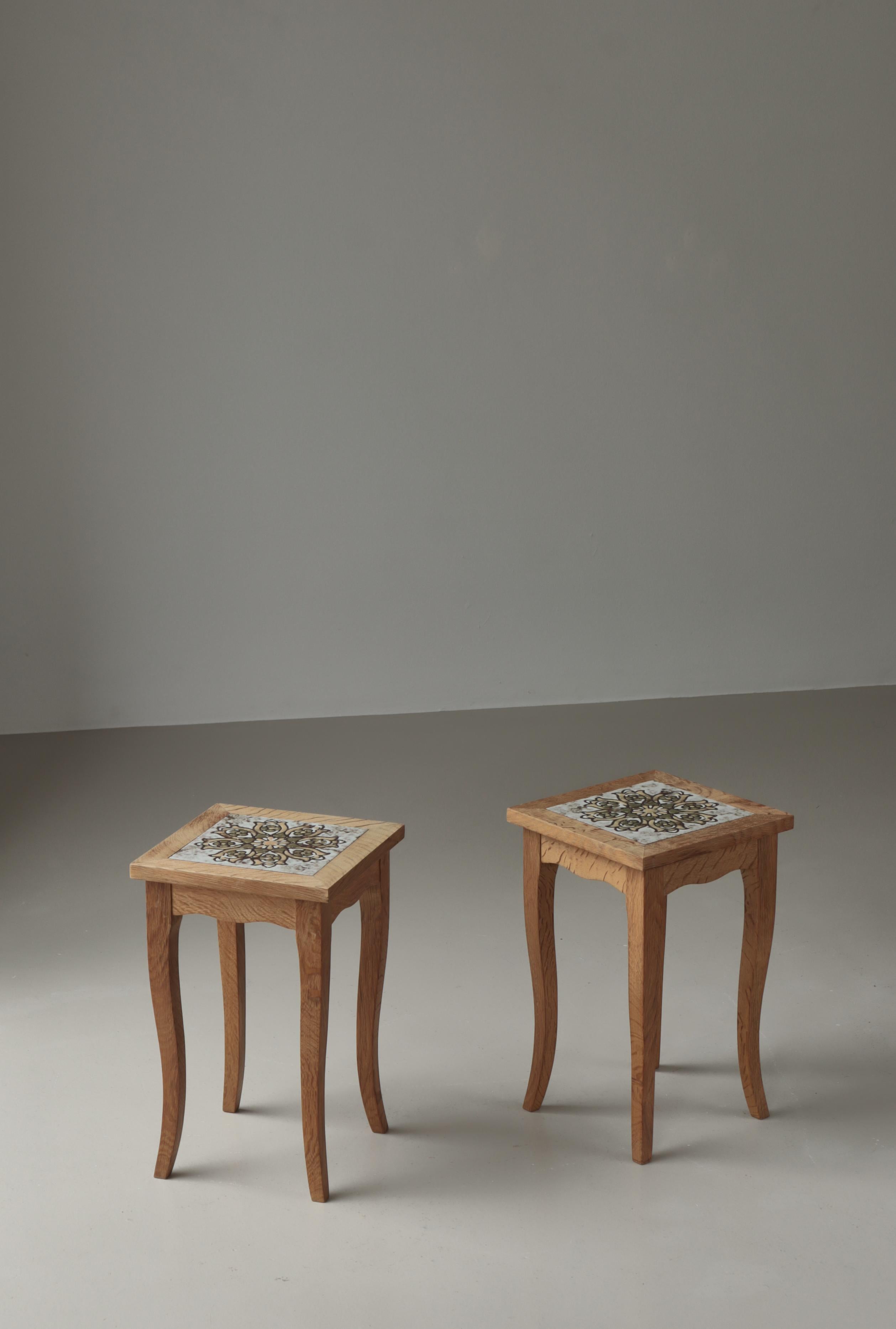 Charming pair of end tables made in Denmark in the 1970s and attributed to Henning Kjærnulf. Executed in solid oakwood with a hand decorated ceramic tile with flower motif.