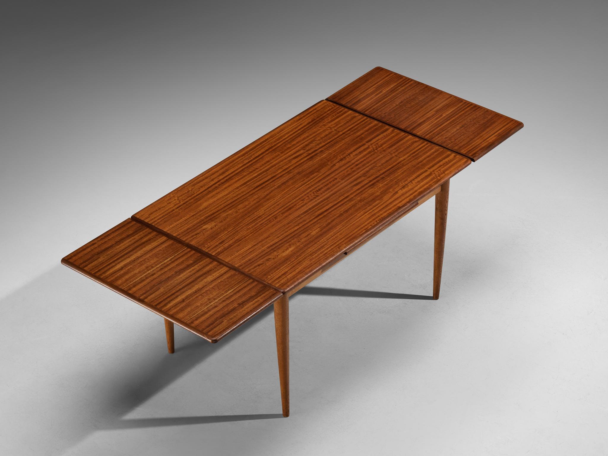 Extendable dining table, mahogany, oak, Scandinavia, 1960s

This Scandinavian Modern extendable dining table from the 1960s features a classic, minimalist design characteristic of the era. The table includes extension leaves that allow it to expand,
