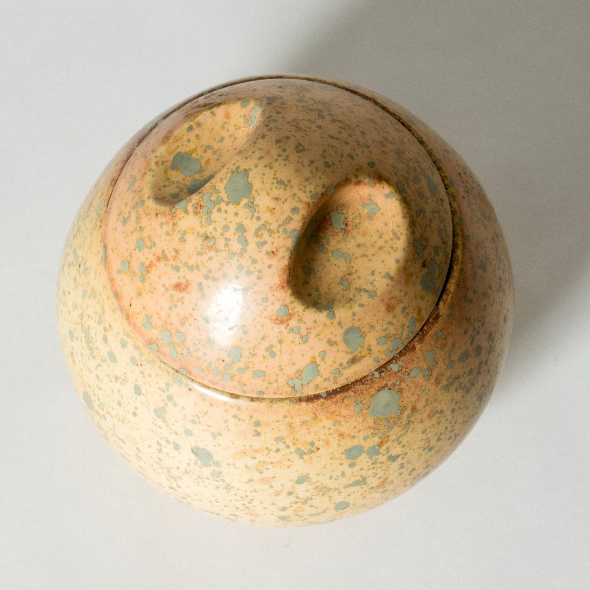Lovely jar by Hans Hedberg, made in faience in thick quality. Plump, egg-shaped form with a lid with oval indentures. Butter-colored glaze with lichen-like flecks giving an organic expression.
