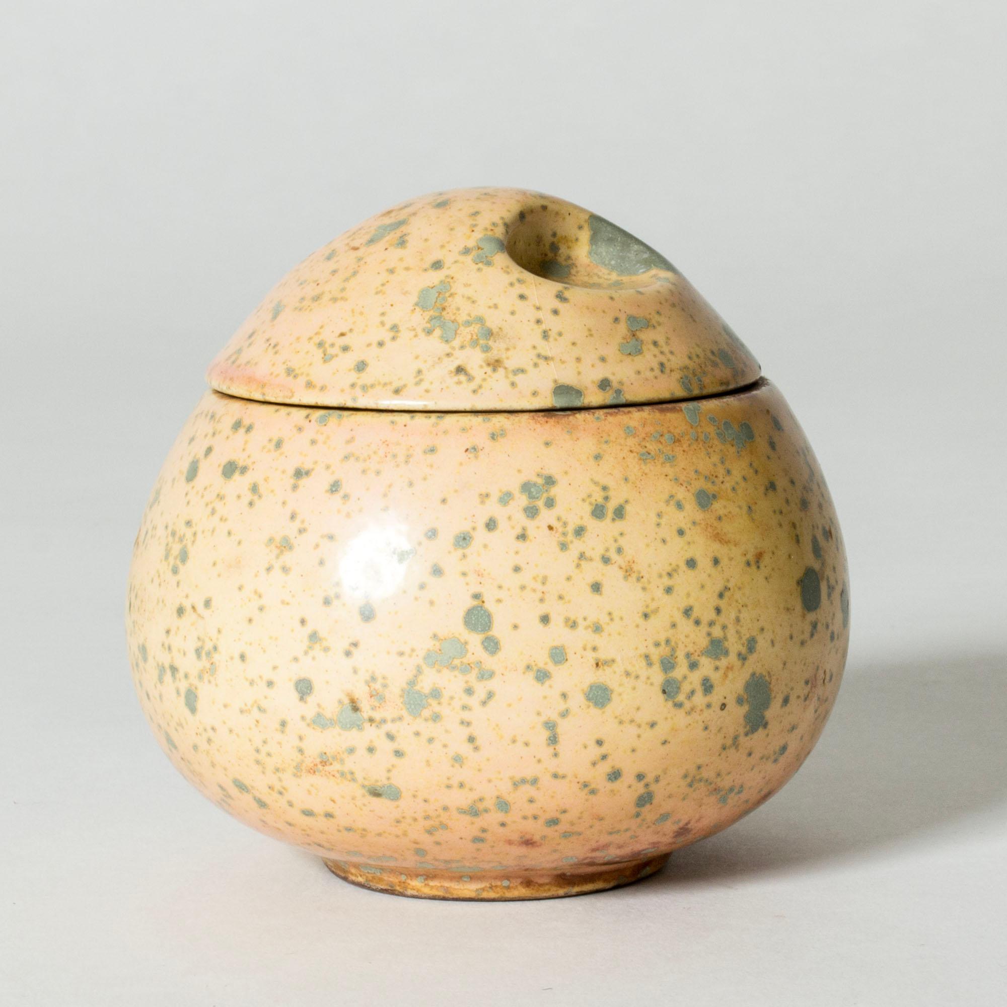 Lovely jar by Hans Hedberg, made in faience in thick quality. Plump, egg-shaped form with a lid with oval indentures. Butter-colored glaze with lichen-like flecks giving an organic expression.