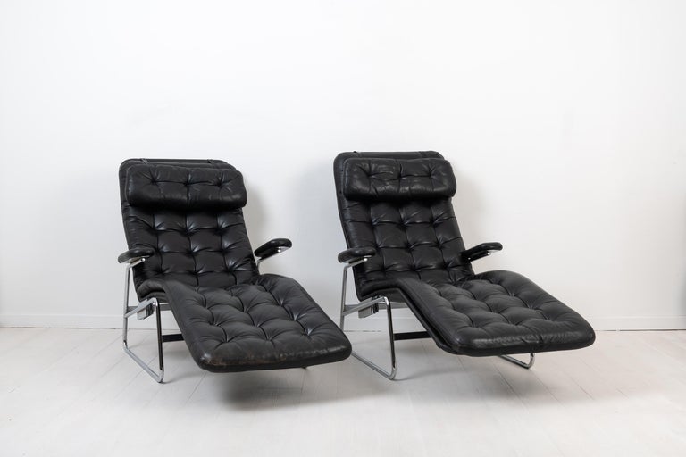 Sam Larsson lounge chairs 'Fenix' for DUX. The chairs are from the second half of the 20th century and an original pair. Chromed metal frame with a canvas seat and detached cushions upholstered in black leather. The head rest is also detachable with