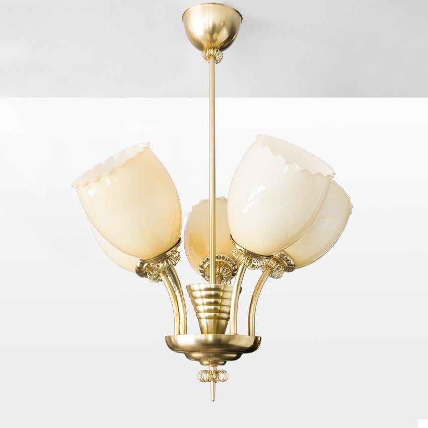 Scandinavian Modern, Finnish Mid-Century Modern pendant in polished brass with five glass shades. The fixture is detailed with circular coils on each arm, finial and canopy. Newly restored and electrified with five standard base sockets for use in