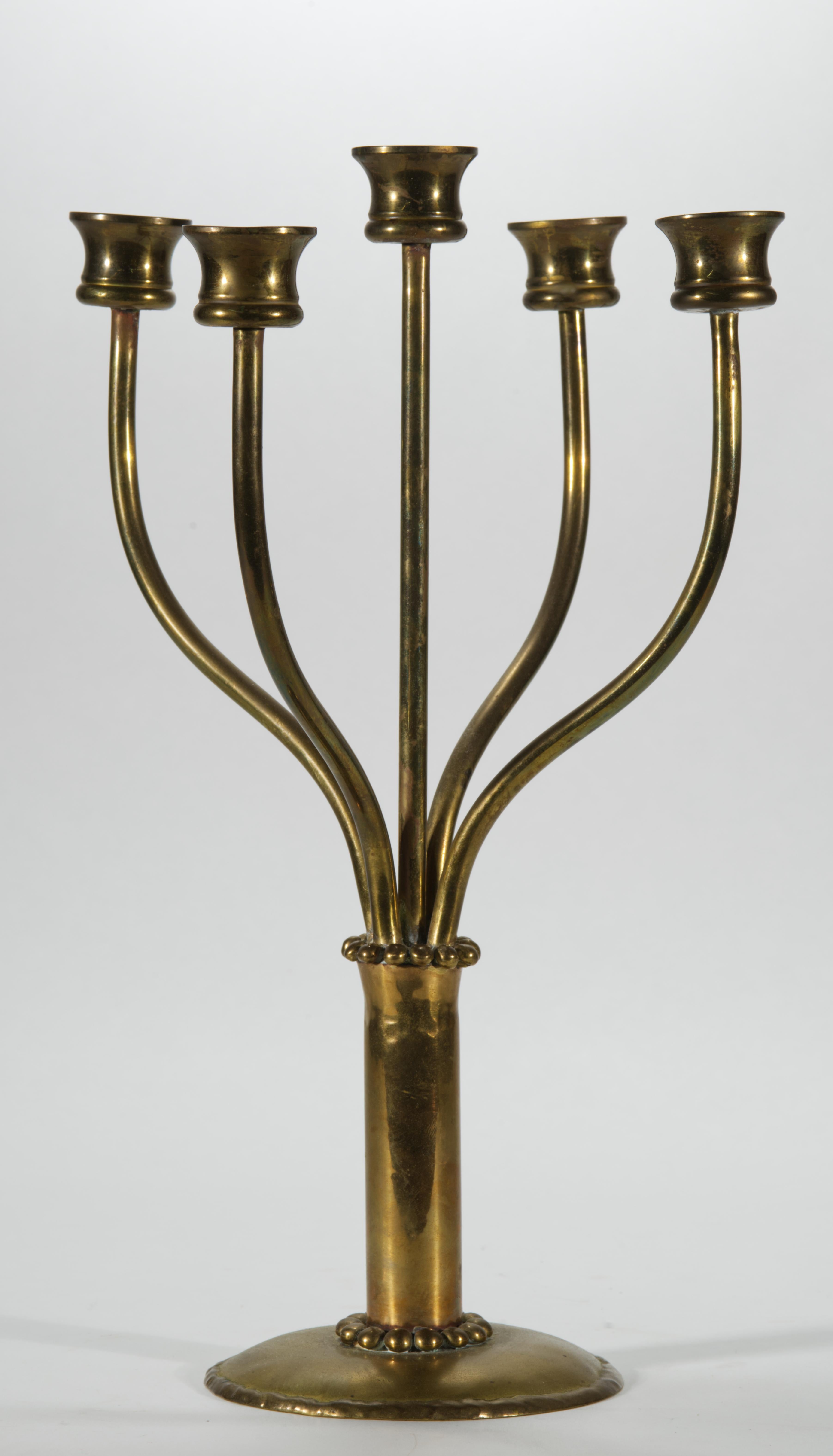 Sculptural vintage candelabra features 5-arm form with 4 curved arms surrounding a slightly taller straight central arm. The circular base and top of the stem are decorated with single rows of textured brass beads; the rim of the base is adorned