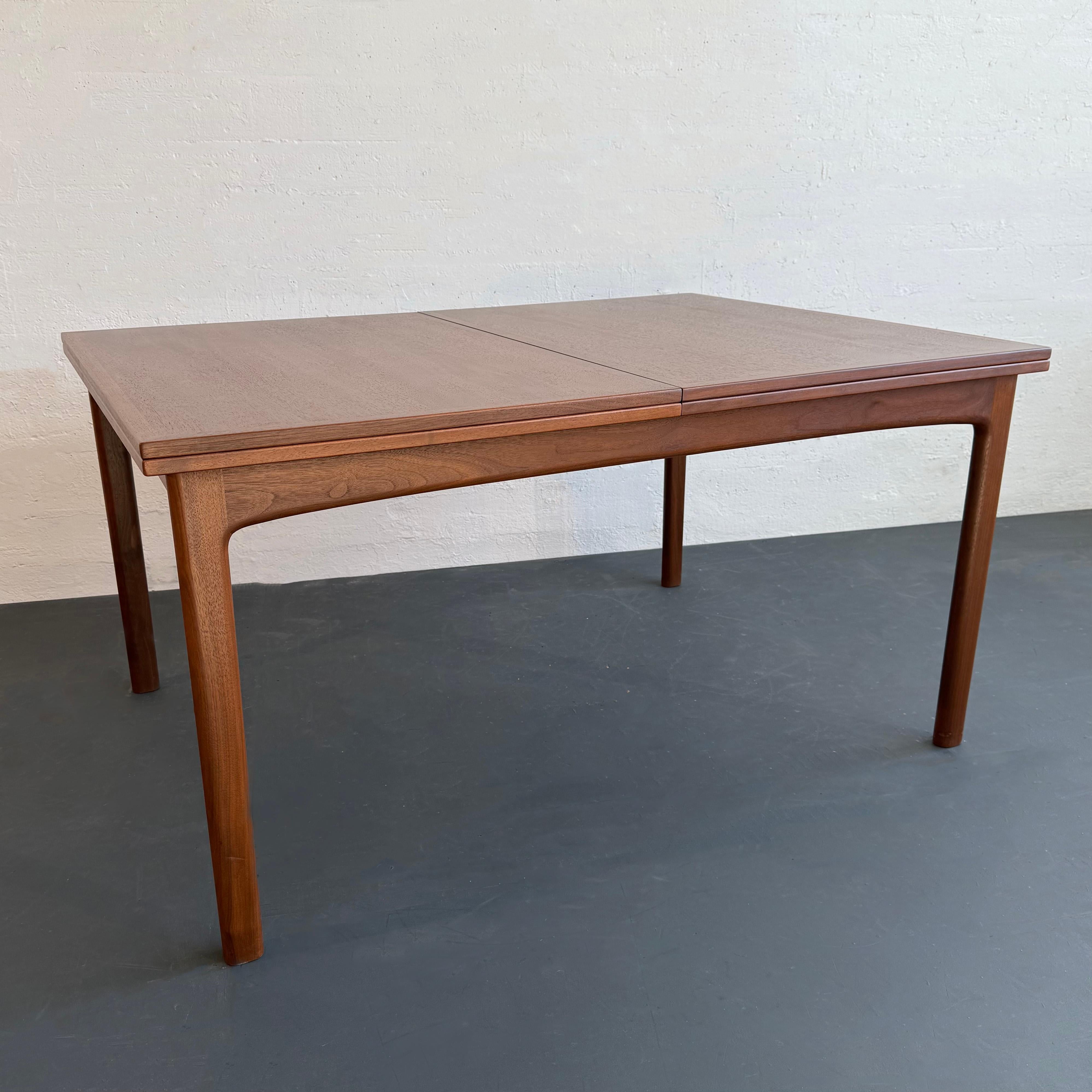 This stylish and rare, Scandinavian modern extension dining table was designed by Folke Ohlsson for DUX of Sweden, circa 1960s. It's made of solid teak and features both practical and distinctive design. The table has been finished in a medium tone