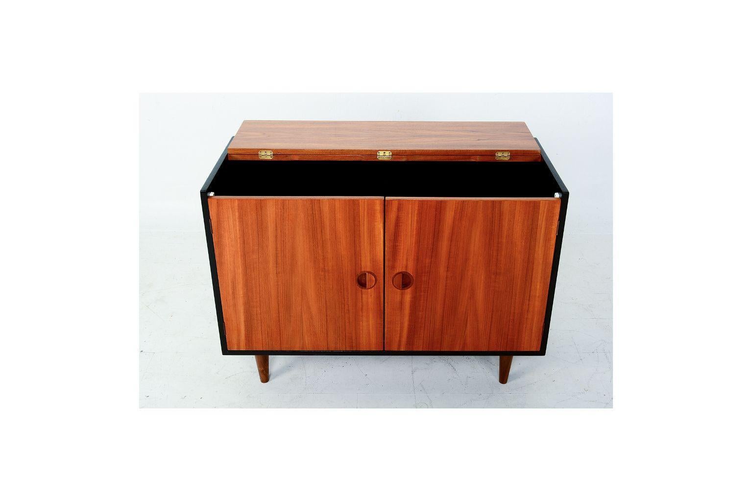For your consideration: Small teak wood cabinet/credenza Scandinavian Modern 1960s. In the manner of Nils Jonsson.

Features clever flip top opening and two easy access front doors. Adjustable shelves. Mounted on peg legs.

Dimensions: H 23 in.