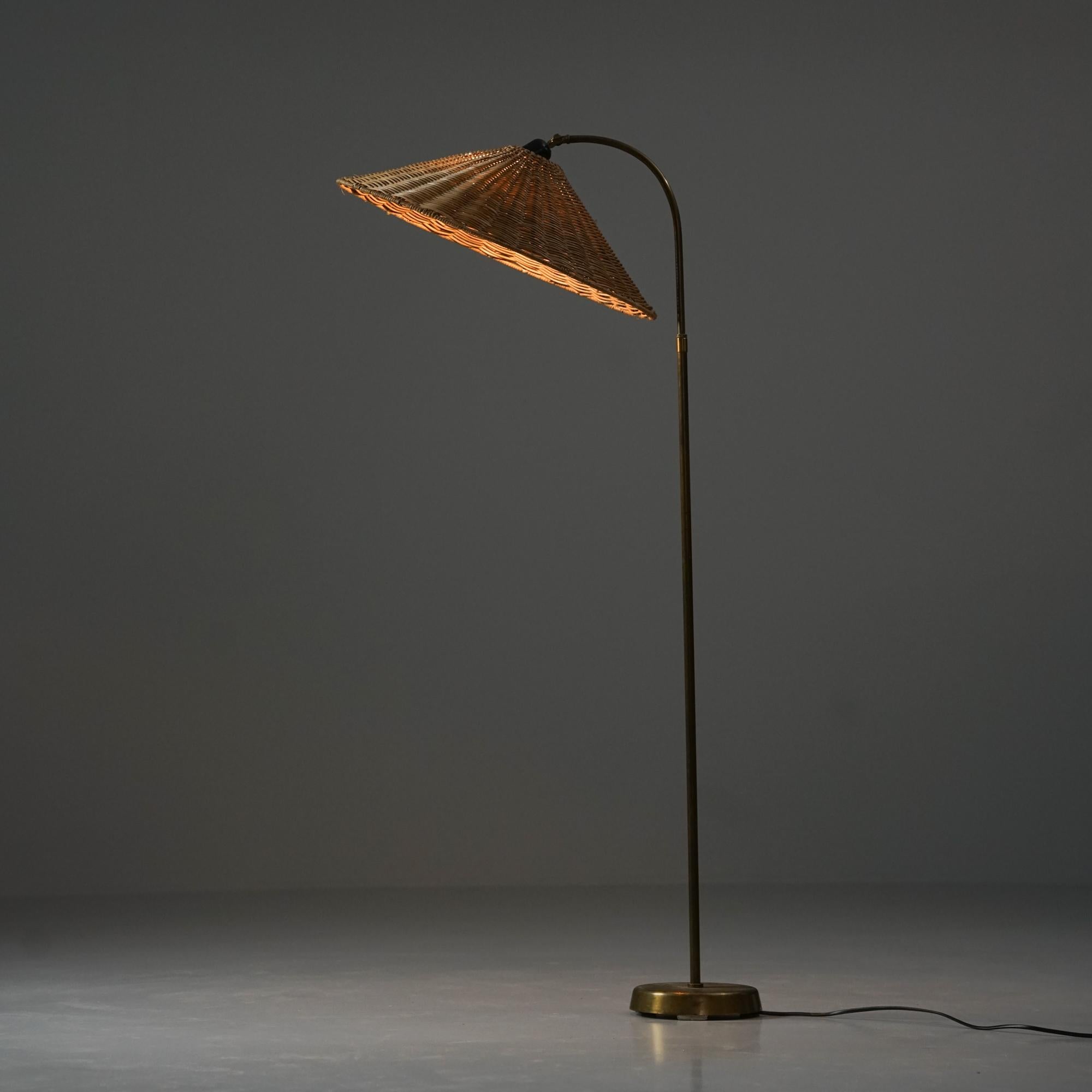 Scandinavian Modern floor lamp, manufactured in Finland, 1950s. Brass frame with renewed rattan weaved lampshade. The lampshade is adjustable. Good vintage condition, minor patina consistent with age and use. 