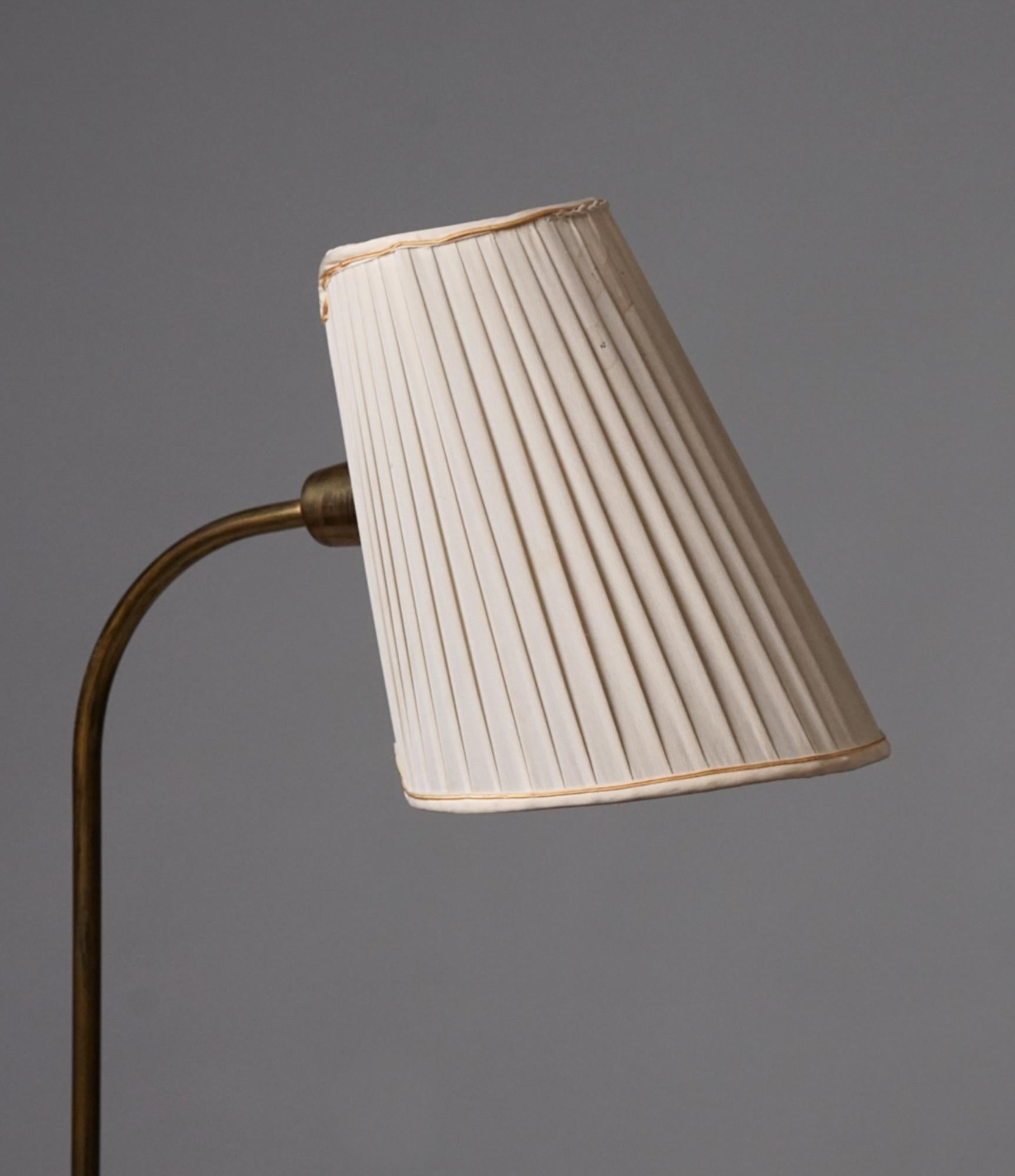 Scandinavian Modern floor lamp, manufactured by Stockmann/Orno Oy, 1950s. Brass with silk lampshade. Good vintage condition, minor patina consistent with age and use. Beautiful minimalistic design. 