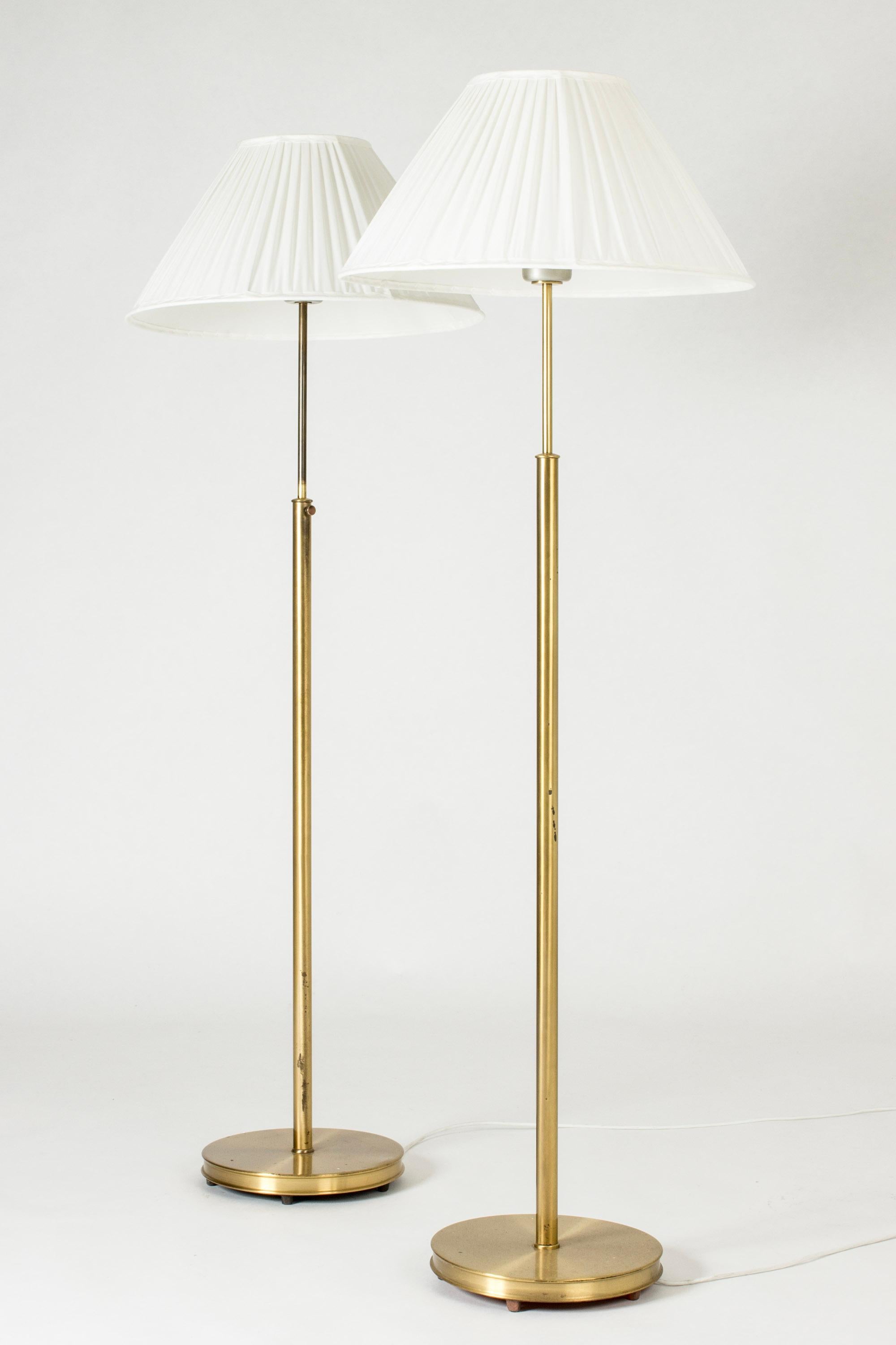 Pair of beautiful brass floor lamps by Josef Frank, made from brass with wide pleated shades. Decorative screws used for adjusting the height. Married couple, small design variation between the stems.