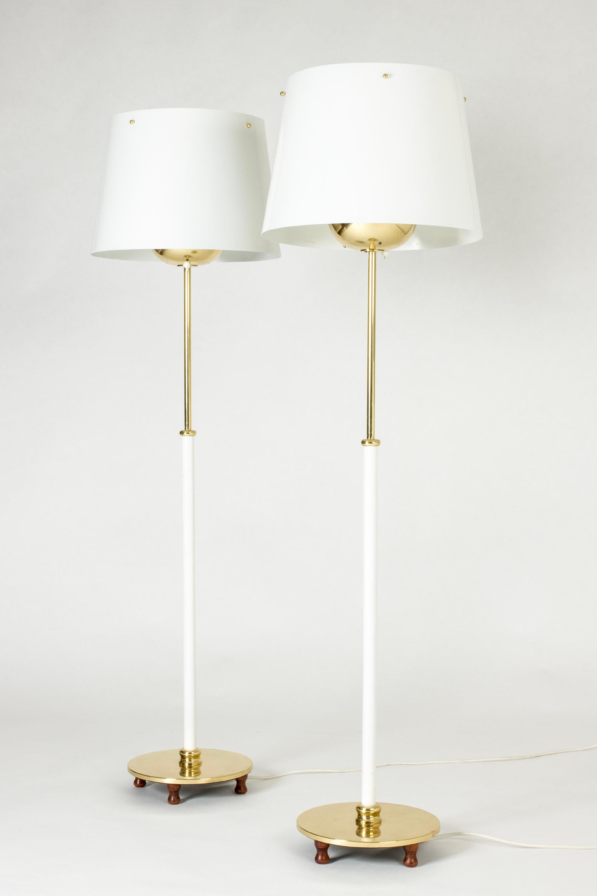 Coppia di eleganti lampade da terra in ottone di Josef Frank, steli laccati di bianco nella parte inferiore. Paralumi in metallo con dettagli in ottone, piedi in legno scolpiti.