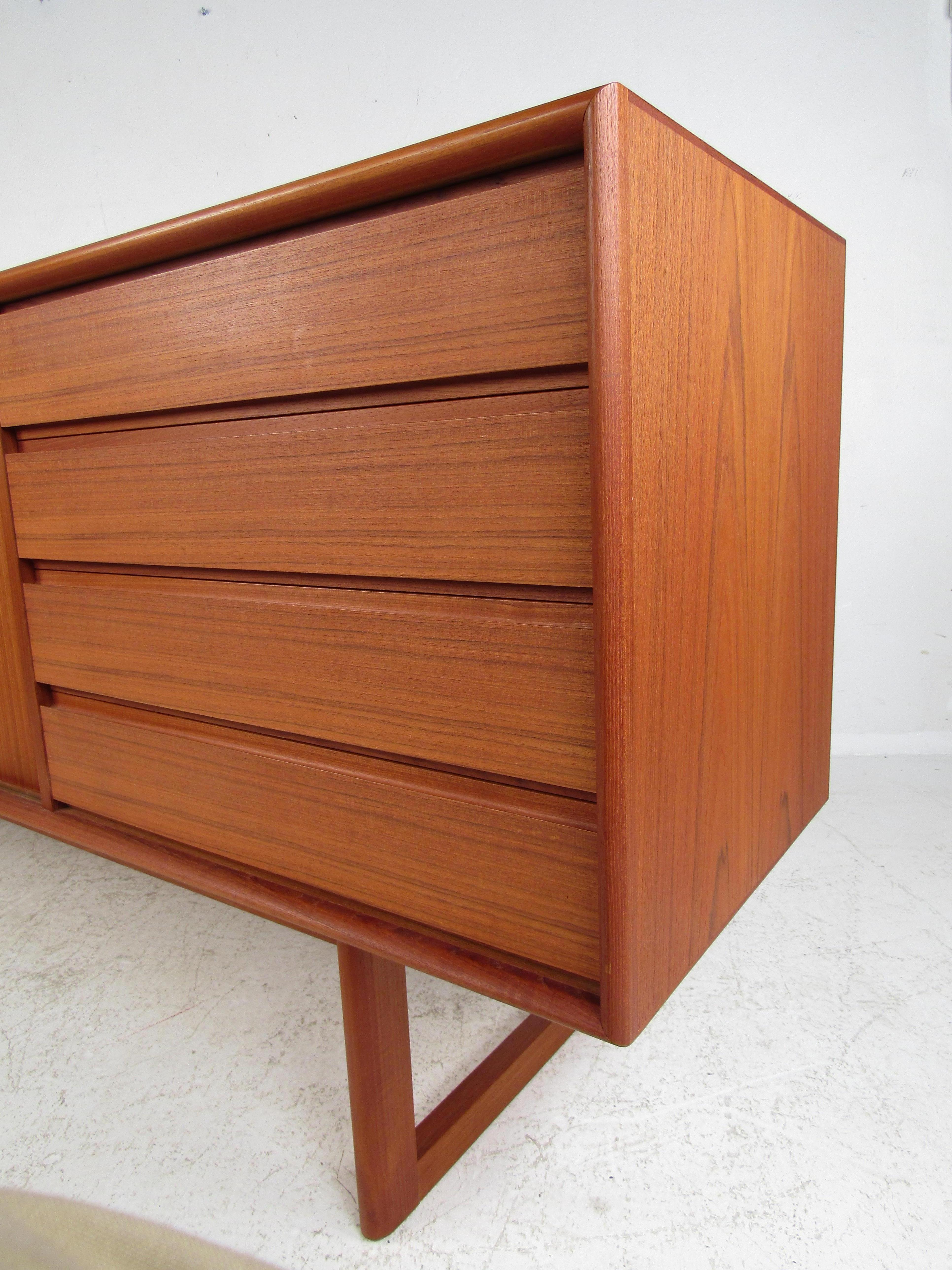 Beautifully constructed Danish teak credenza with four drawers and two sliding door storage compartments with adjustable shelves. Clean, understated, design details add versatility to a variety of applications such as an office credenza, dining room