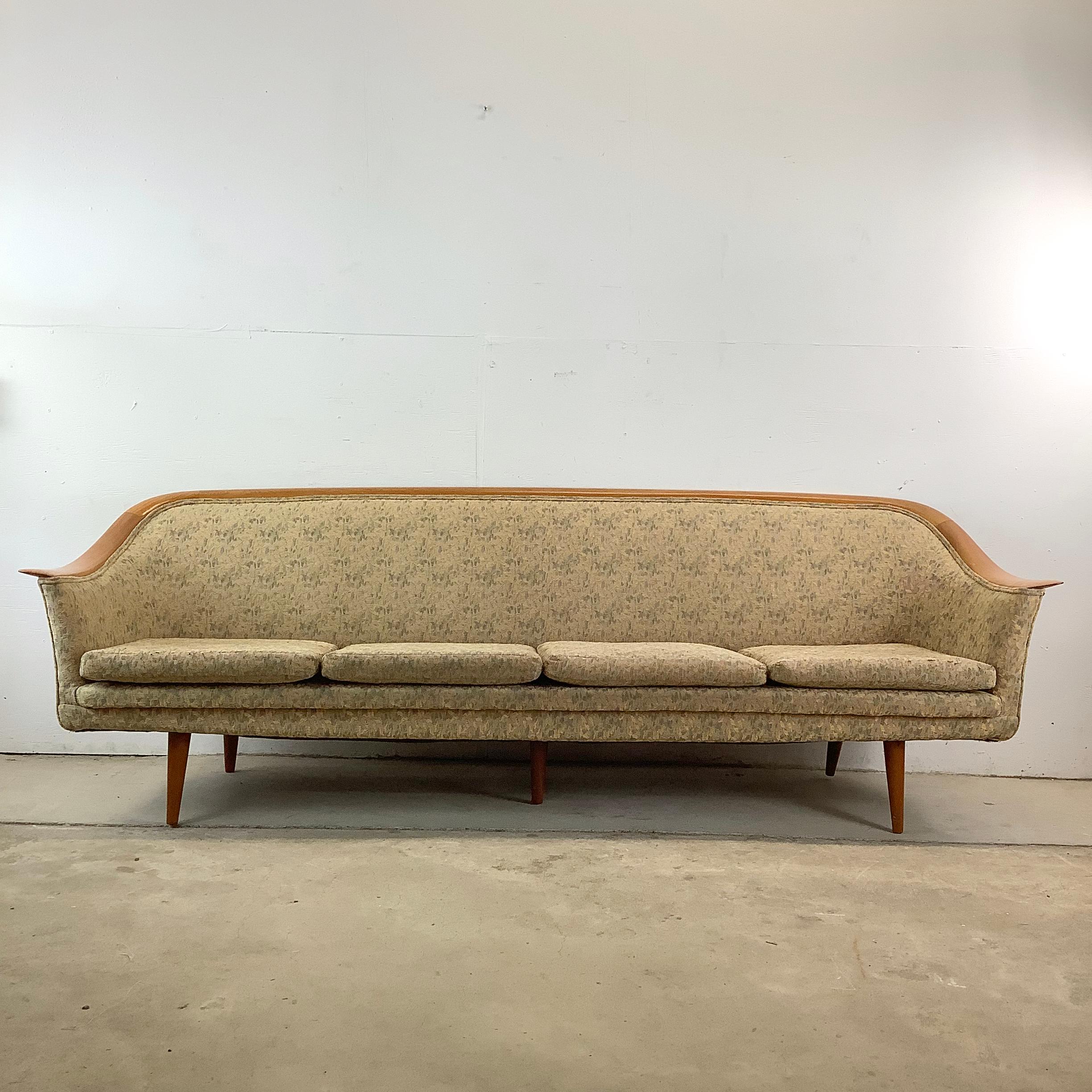Celebrate the best of vintage and modern with this Danish Modern four-seat sofa, attributed to Fredrik Kayser. The frame features smooth, sculpted wood trim along the backrest—perfectly curved and seamlessly integrated—and is paired with tapered