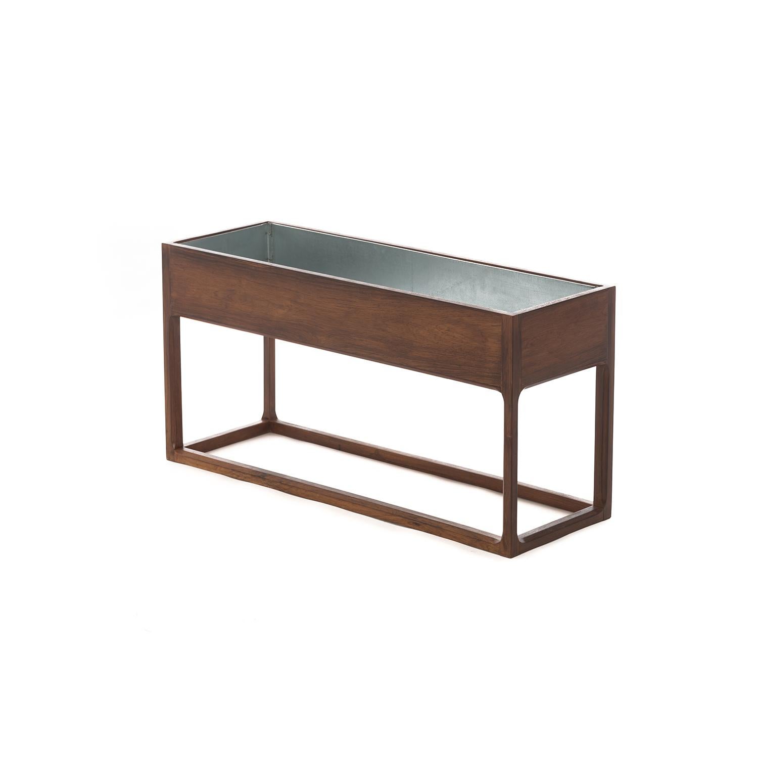 This elegant planter features a frame style base with a jewel-cutout detail on the inner legs. Rosewood is deeply figured and finished in a durable lacquer, which has been updated. Aluminum liner is removable for easy cleaning. Perfect to set pots