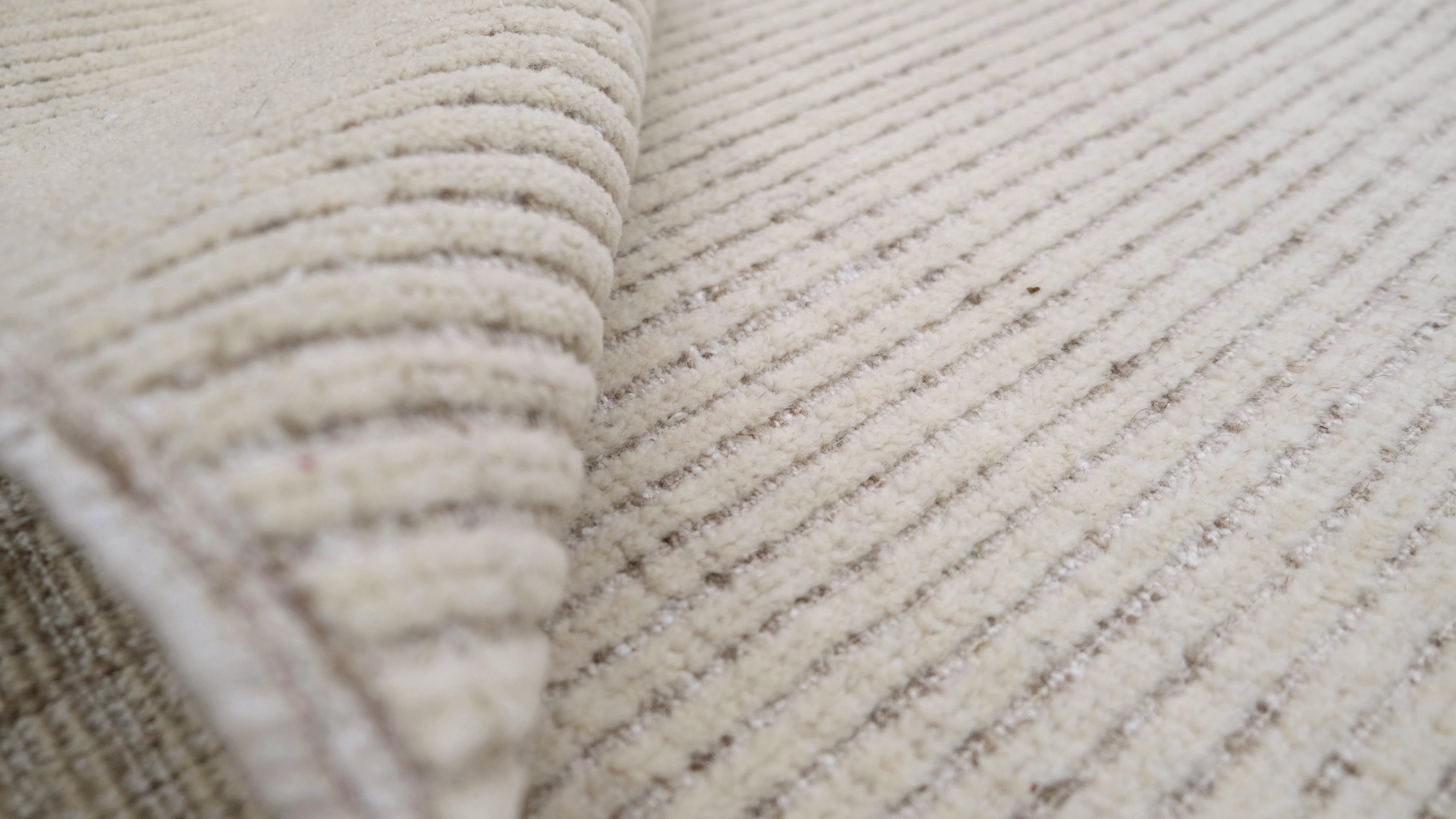 Bringen Sie mit diesem exquisiten, handgeknüpften Wollteppich schlichte Eleganz in Ihren Raum. Mit seinem subtilen geometrischen Muster aus konzentrischen Linien, die ein raffiniertes Starburst-Motiv bilden, bietet dieser Teppich ein elegantes,