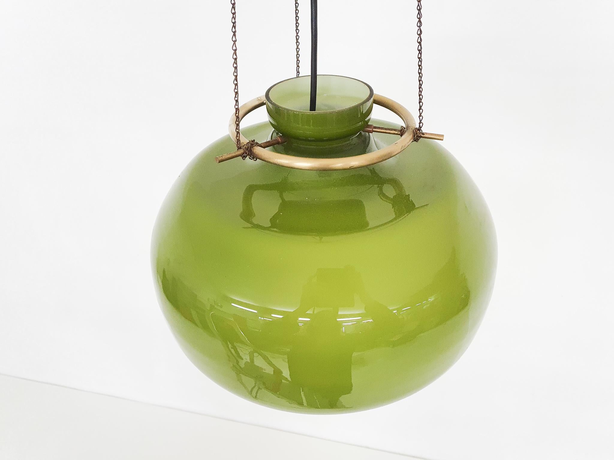 Lampada a sospensione in vetro verde appesa a catene di ottone.
Il colore del vetro diventa giallo quando viene acceso.