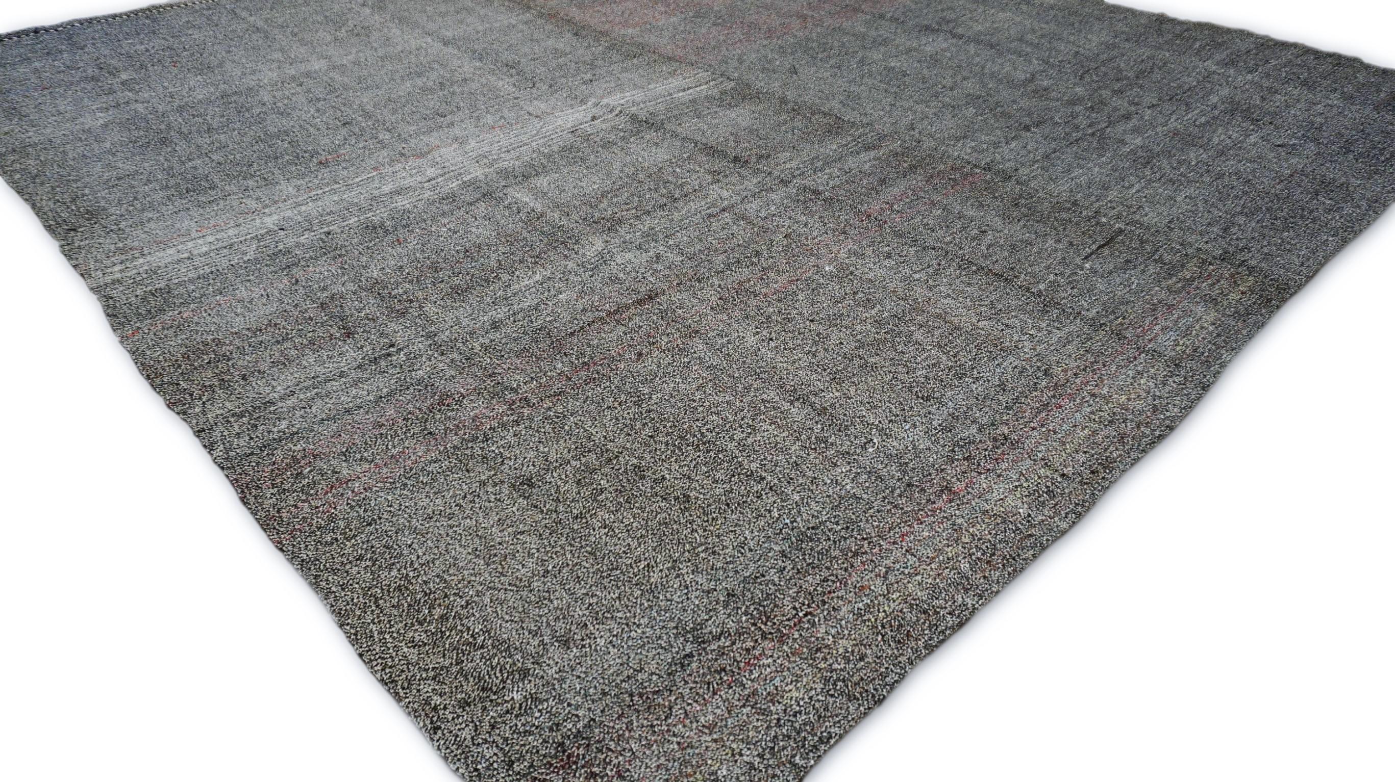 Questo  Il kilim in lana e pelo di capra incarna l'essenza della raffinatezza minimalista e dell'artigianato senza tempo. Caratterizzato da un sottile gioco di toni grigi, antracite, bianchi e rosa, questo pezzo è un'elegante rappresentazione delle