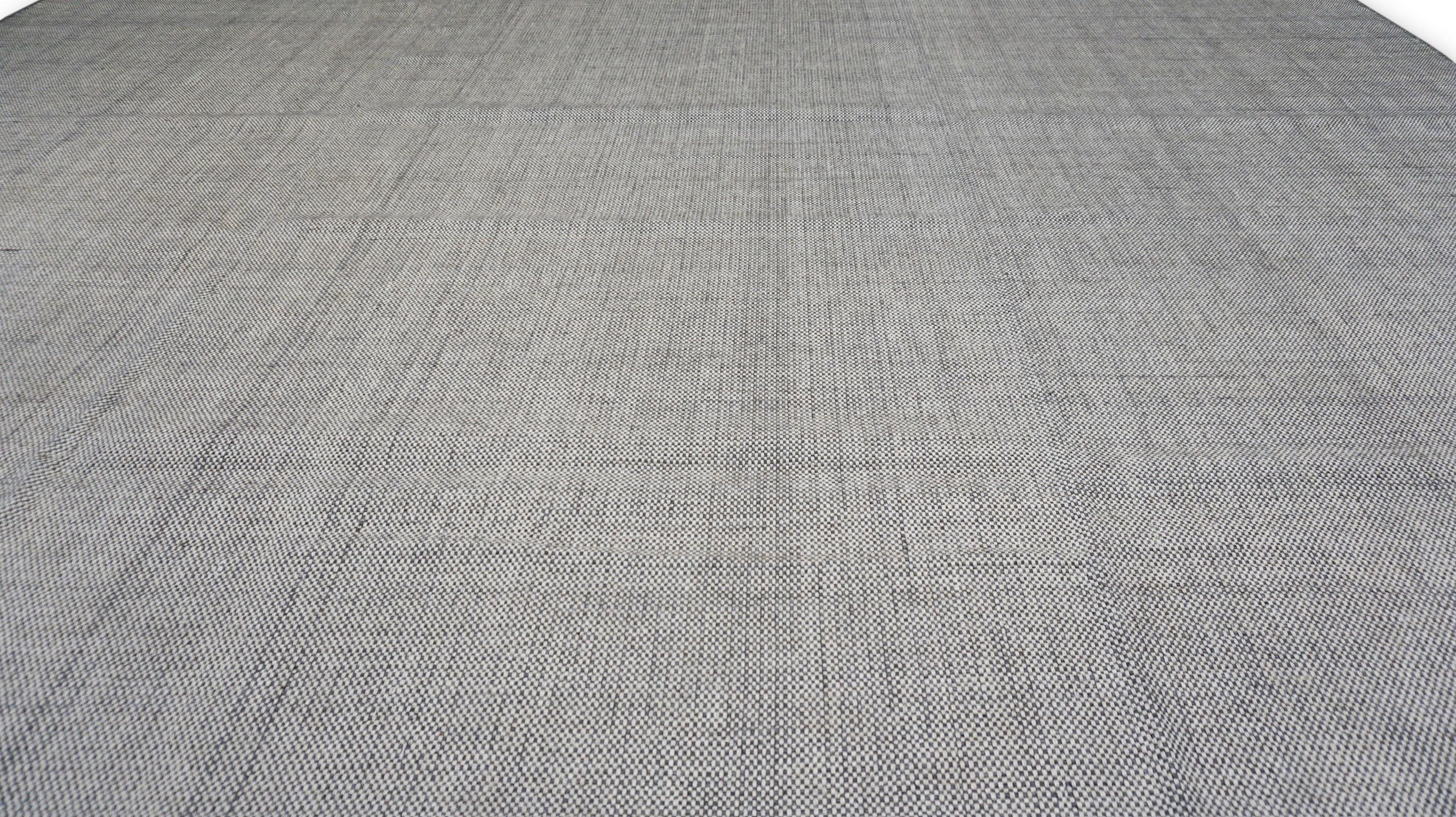 Esta alfombra de lana tejida a mano ofrece una refinada estética minimalista con una sensibilidad moderna. Con un campo sólido en suaves tonos grises, los sutiles cambios tonales de la alfombra y la delicada textura de su tejido la convierten en la
