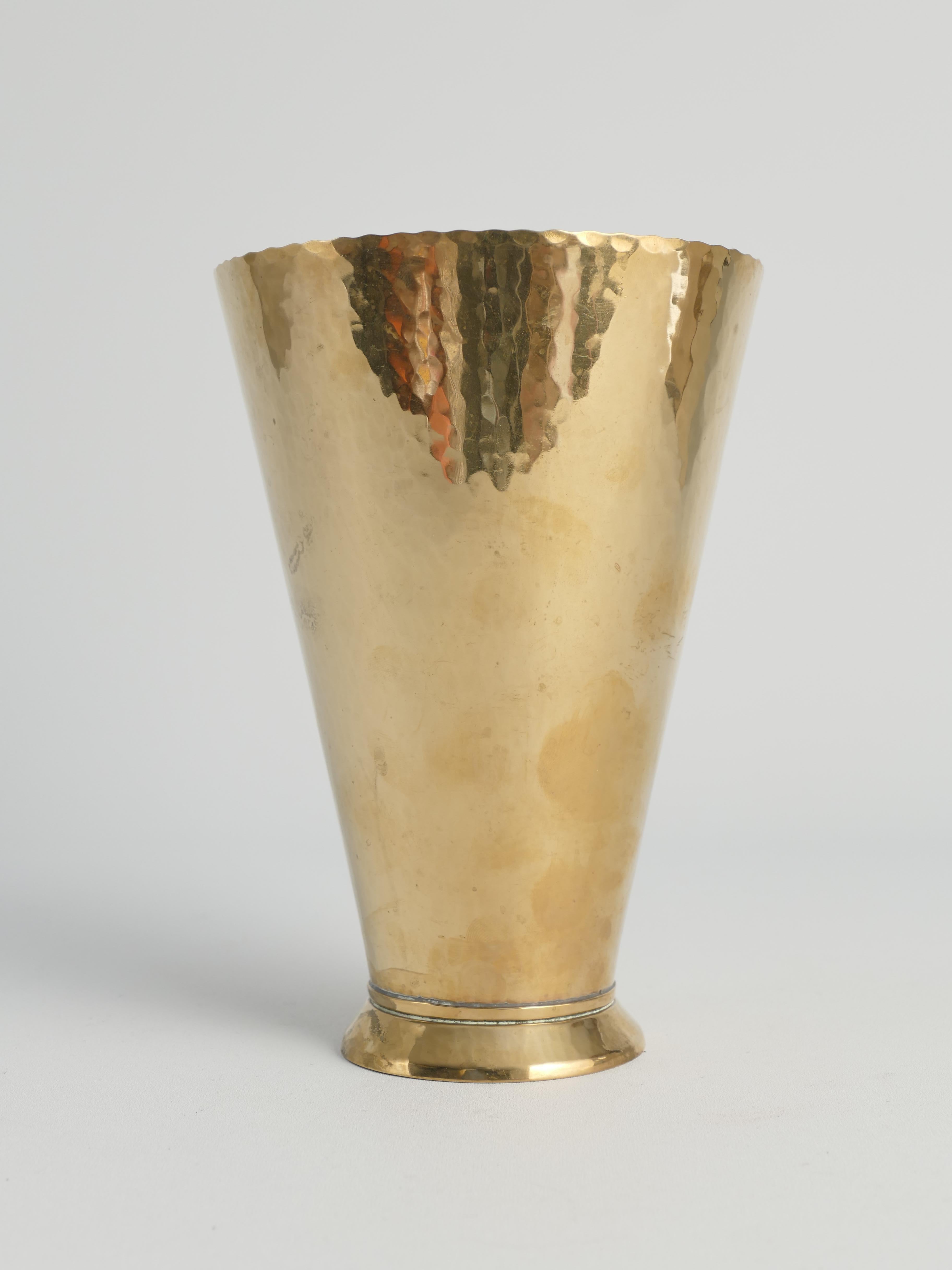 Questo squisito vaso in ottone fatto a mano in Svezia, realizzato nel 1949, incarna l'eleganza e la semplicità tipiche del design moderno scandinavo. Il vaso ha una forma conica elevata su un piccolo piede, che permette ai fiori di diffondersi