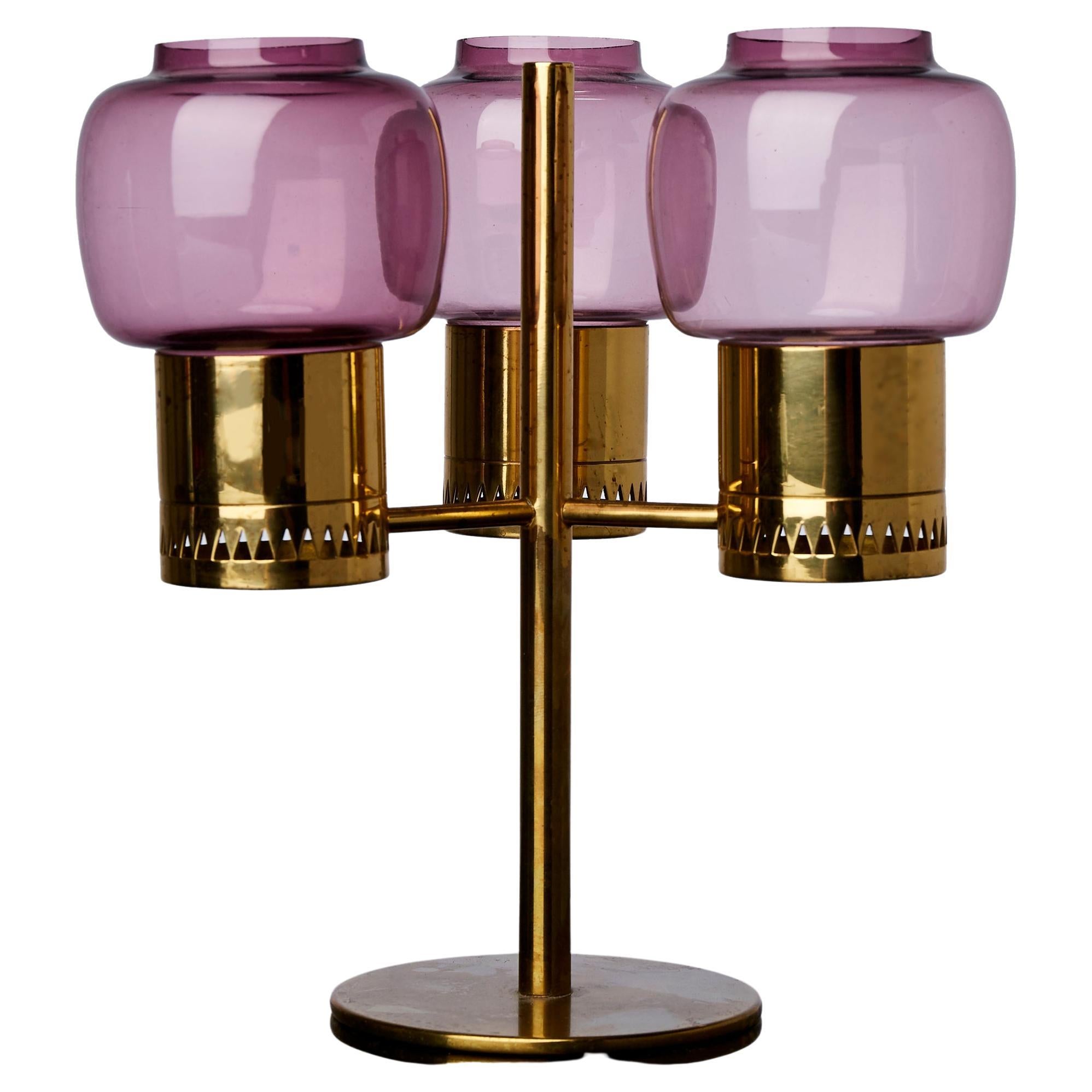 Scandinavian Modern Hans-Agne Jakobsson three armed candle holder in brass with a smashing lilac/pink color designed for Hans-Agne Jakobsson Markaryd, AB Sweden, 1950s. Polished brass and hand blown with fabulous and rare lilac pink glass shades,